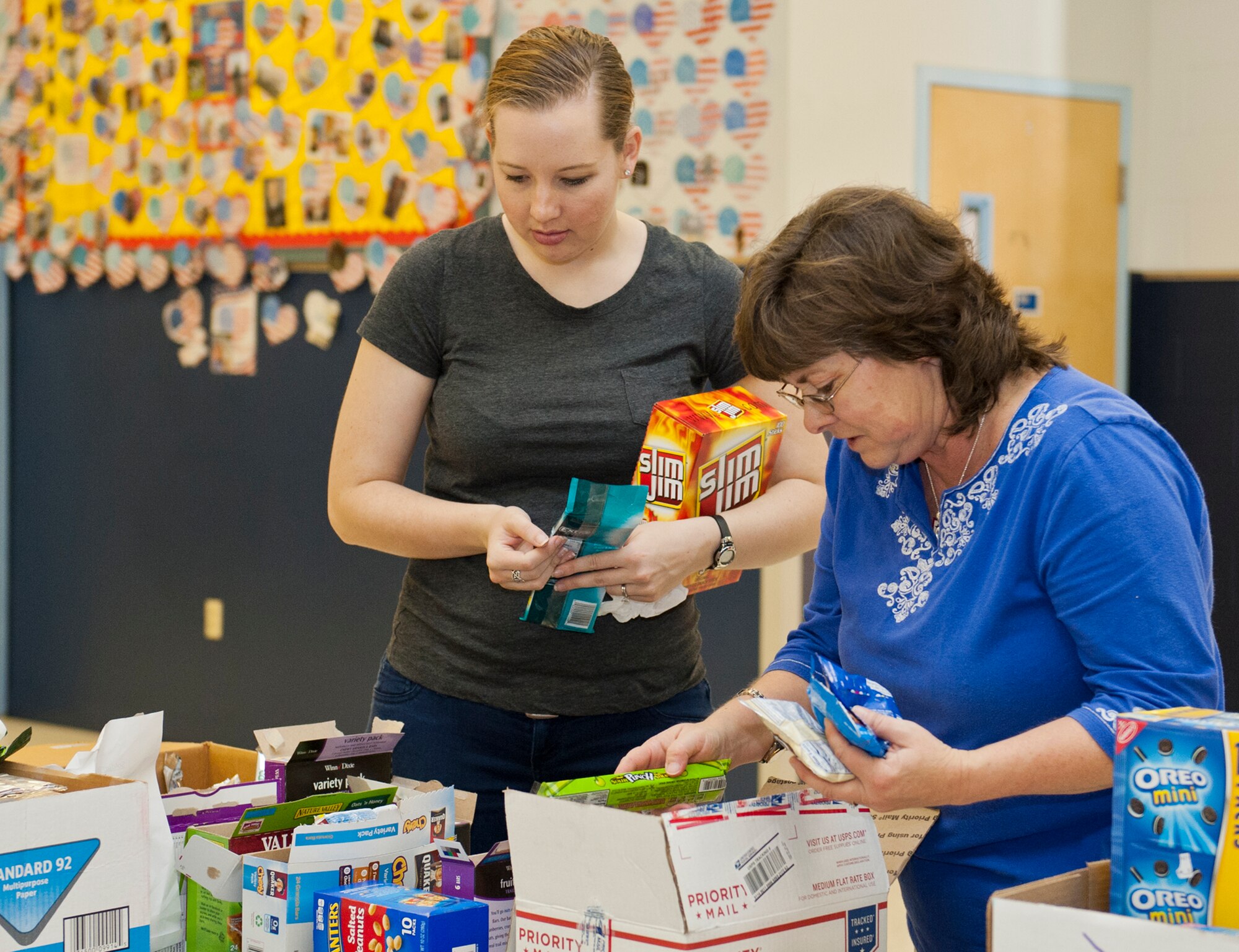 2nd Lt. Rachel Lyons, with the 96th Logistics Readiness Squadron and Deb Hutto, volunteer and member of the Northwest Florida Blue Star Mothers, sort donated items to be mailed in care packages at the Eglin Elementary School cafeteria during the troop care drive Dec. 5. The Company Grade Officer’s Council collected 2,500 cards, letters and drawings from local schools and the Red Cross. These cards, letters and drawings were included in the care packages along with books, coffee, magazines, snacks and various comfort items. The items were donated by various community businesses and organizations, and the CGOC, who also hosted the event. Volunteers packed a total of 92 care packages for Eglin’s deployed. (U.S. Air Force photo/Ilka Cole)