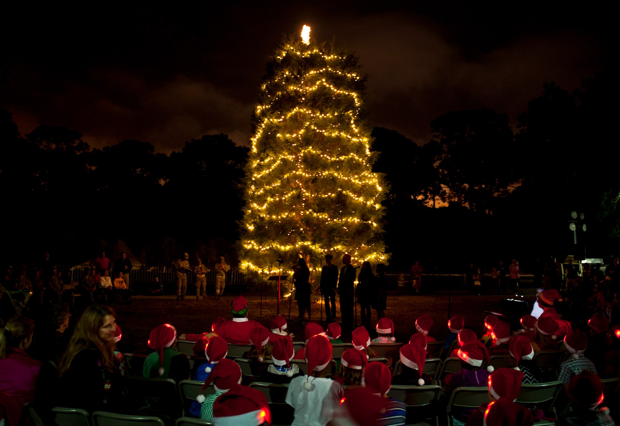 Donned in Santa hats, children from the Chapel’s Camp Kids Choir, led by Audrey Bonnano and accompanied by Marilyn Anderson on the keyboard, sang Christmas carols during the Eglin’s traditional tree lighting ceremony at the West Gate Chapel Dec. 5. Chaplain, Capt. Micah Baker, led the festivities with a moment of prayer.  During the base event, the winner of the base life-sized card decoration contest was announced.  Brig. Gen. David Harris, 96th Test Wing commander also addressed the crowd with messages of peace and goodwill before lighting the tree. The chapel sponsored a reception with entertainment and refreshments after Santa Claus arrived by fire truck. (U.S. Air Force photo/Ilka Cole)