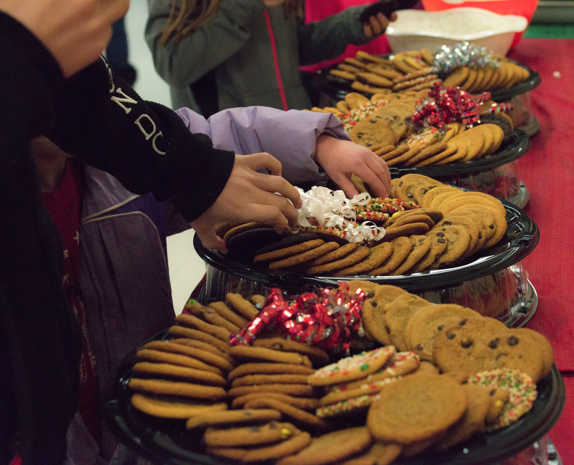 Children grab cookies at the Liberty Chapel, Mountain Home Air Force Base, Idaho, Dec. 5, 2014, after the holiday parade. The chapel hosted a tree lighting ceremony and provided light refreshments such as cookies and hot chocolate for the base community. (U.S. Air Force photo by Airman 1st Class Jessica Smith/RELEASED)