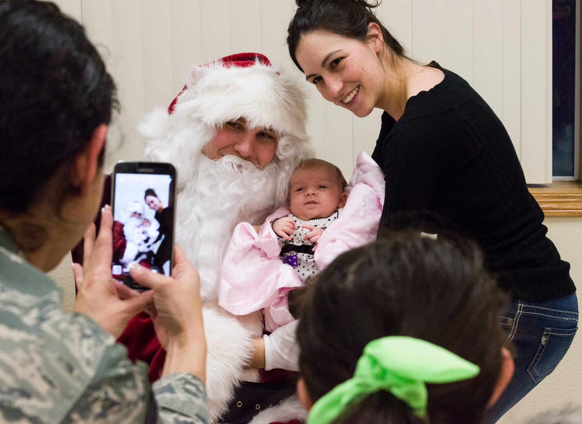 A family poses for a photo with Santa in the Liberty Chapel at Mountain Home Air Force Base, Idaho, Dec. 5, 2014. The base community came together to celebrate the holidays with refreshments and caroling. (U.S. Air Force photo by Airman 1st Class Jessica Smith/RELEASED)