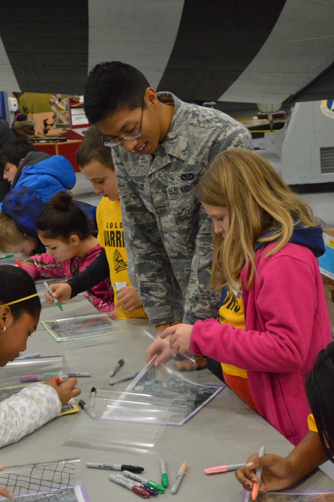 Richard Carillo, 436th Civil Engineer Squadron engineering journeyman, assists local 5th graders at the "Aerial Take Home 2" station during Geographic Information System (GIS) Day Nov. 19, 2014, at the Air Mobility Command Museum on Dover Air Force Base, Del. There were 300 students from five local elementary schools that were guided through 17 stations by 436th CES engineering assistants and other volunteers. (Courtesy Photo)