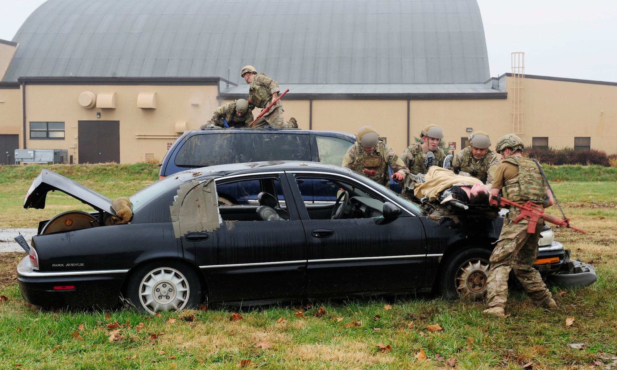 Three teams of four Airmen transport simulated patients over a vehicles while keeping a look out for enemy fire during a Tactical Combat Casualty Care training exercise at Scott Air Force Base, Ill., Dec. 4, 2014. The goal of the teams was two get their patients to a location where they would be transported to a higher echelon of care. The teams all made up Airmen from the 375th Air Mobility Wing and 932nd Airlift Wing Explosive Ordnance flights had four roles, a medic, medical assistant, a team leader and one security member. (U.S. Air Force photo/ Staff Sgt. Stephenie Wade)