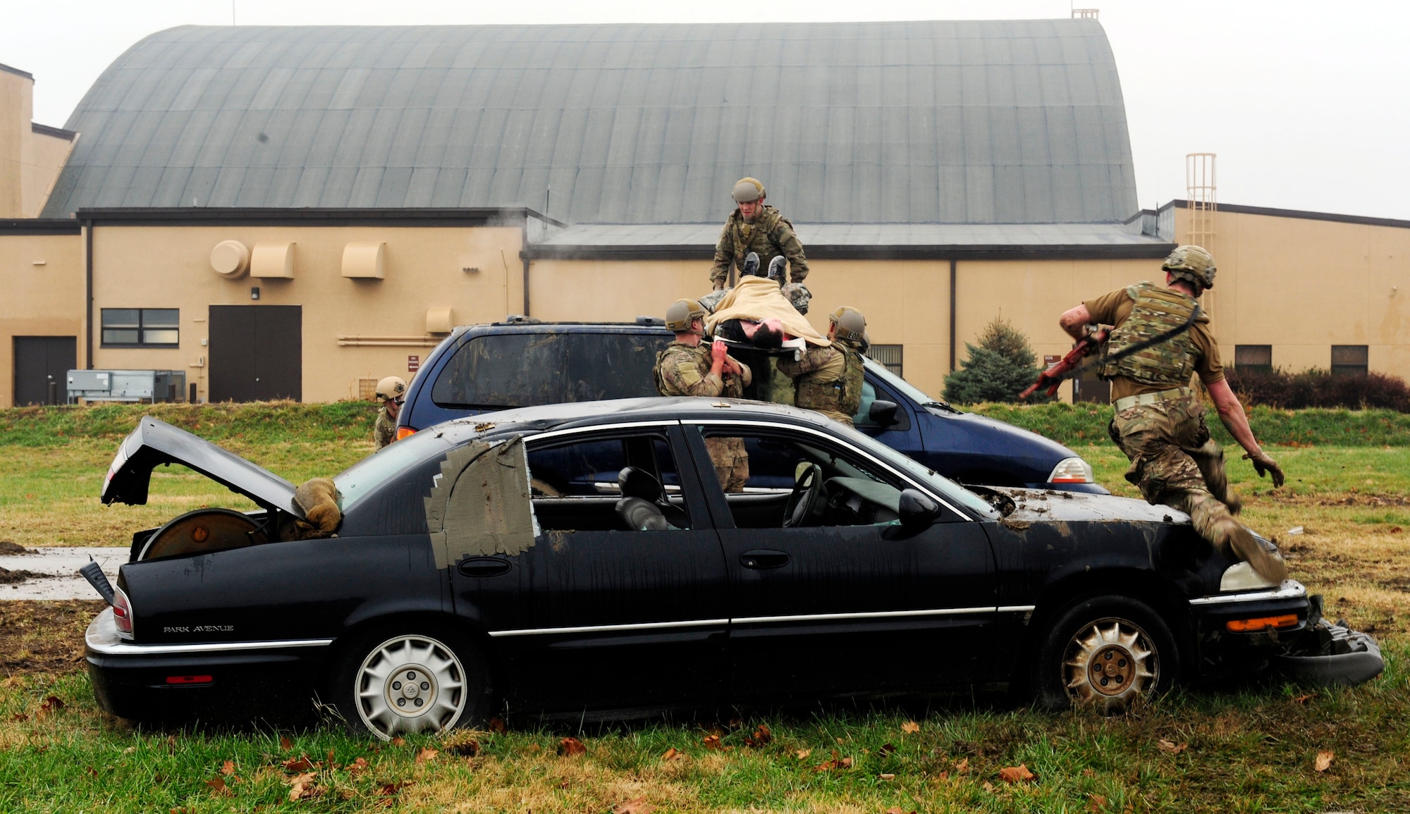 Three teams of four Airmen transport simulated patients over a vehicles while keeping a look out for enemy fire during a Tactical Combat Casualty Care training exercise at Scott Air Force Base, Ill., Dec. 4, 2014. The goal of the teams was two get their patients to a location where they would be transported to a higher echelon of care. The teams all made up Airmen from the 375th Air Mobility Wing and 932nd Airlift Wing Explosive Ordnance flights had four roles, a medic, medical assistant, a team leader and one security member. (U.S. Air Force photo/ Staff Sgt. Stephenie Wade)