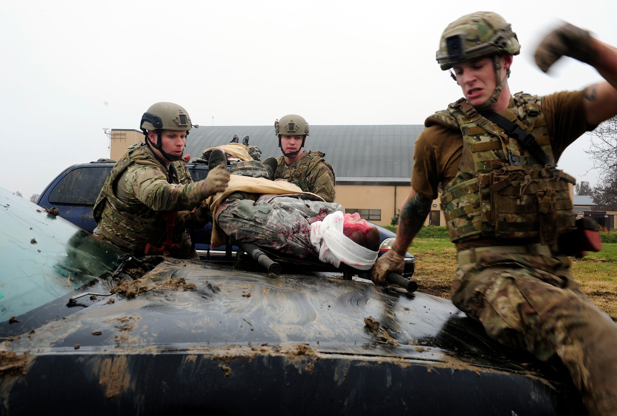 Three teams of four Airmen transport simulated patients over a vehicles while keeping a look out for enemy fire during a Tactical Combat Casualty Care training exercise at Scott Air Force Base, Ill., Dec. 4, 2014. The goal of the teams was two get their patients to a location where they would be transported to a higher echelon of care. The teams all made up Airmen from the 375th Air Mobility Wing and 932nd Airlift Wing Explosive Ordnance flights had four roles, a medic, medical assistant, a team leader and one security member. (U.S. Air Force photo/ Staff Sgt. Stephenie Wade)
