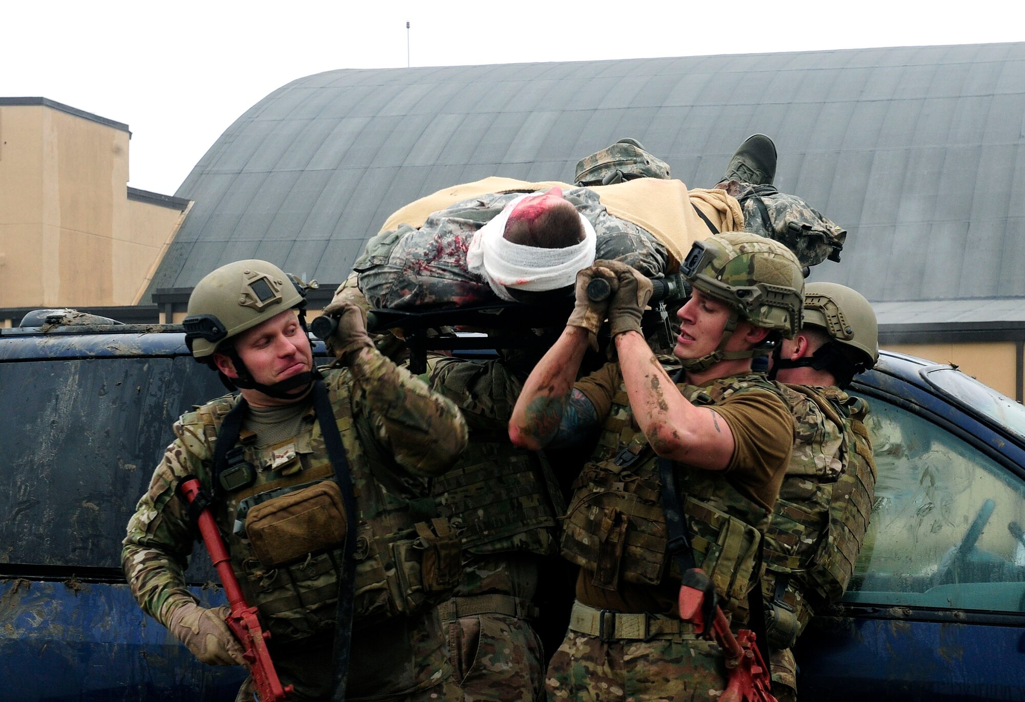 Three teams of four Airmen transport simulated patients over a vehicles while keeping a look out for enemy fire during a Tactical Combat Casualty Care training exercise at Scott Air Force Base, Ill., Dec. 4, 2014. The goal of the teams was two get their patients to a location where they would be transported to a higher echelon of care. The teams all made up Airmen from the 375th Air Mobility Wing and 932nd Airlift Wing Explosive Ordnance flights had four roles, a medic, medical assistant, a team leader and one security member. (U.S. Air Force photo/ Staff Sgt. Stephenie Wade)