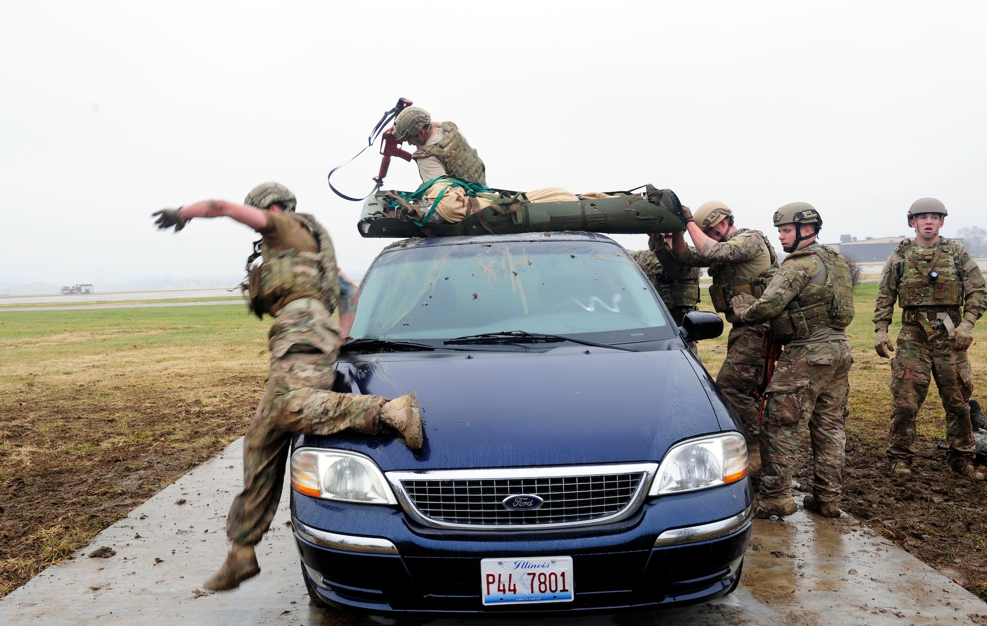 Three teams of four Airmen transport simulated patients over a vehicles while keeping a look out for enemy fire during a Tactical Combat Casualty Care training exercise at Scott Air Force Base, Ill., Dec. 4, 2014. The goal of the teams was two get their patients to a location where they would be transported to a higher echelon of care. The teams all made up Airmen from the 375th Air Mobility Wing and 932nd Airlift Wing Explosive Ordnance flights had four roles, a medic, medical assistant, a team leader and one security member. (U.S. Air Force photo/ Staff Sgt. Stephenie Wade)