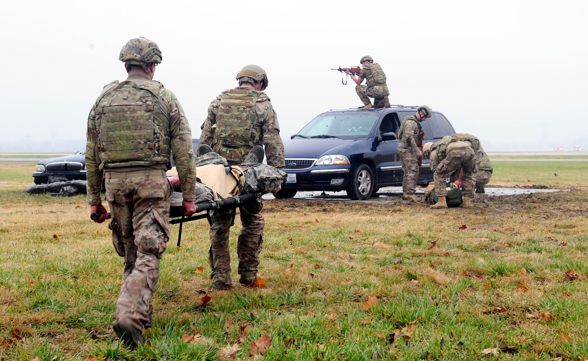 Three teams of four Airmen transport simulated patients over a vehicles while keeping a look out for enemy fire during a Tactical Combat Casualty Care training exercise at Scott Air Force Base, Ill., Dec. 4, 2014. The goal of the teams was two get their patients to a location where they would be transported to a higher echelon of care. The teams all made up Airmen from the 375th Air Mobility Wing and 932nd Airlift Wing Explosive Ordnance flights had four roles, a medic, medical assistant, a team leader and one security member. (U.S. Air Force photo/ Staff Sgt. Stephenie Wade)