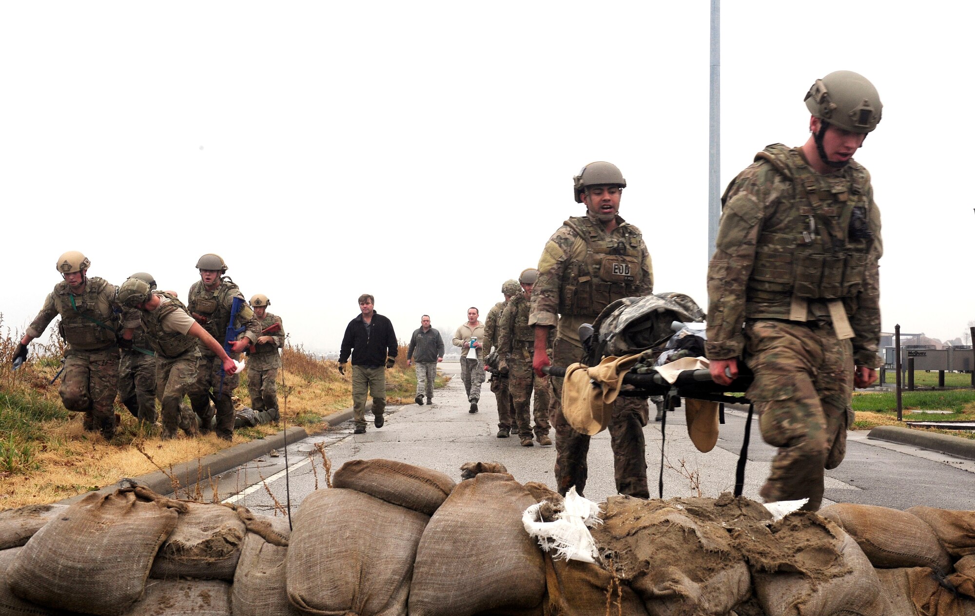 Three teams of four Airmen transport a simulated patient while receiving fire during a Tactical Combat Casualty Care training exercise at Scott Air Force Base, Ill., Dec. 4, 2014. The teams all made up Airmen from the 375th Air Mobility Wing and 932nd Airlift Wing Explosive Ordnance flights had four roles, a medic, medical assistant, a team leader and one security member. T-CCC is a set of lifesaving procedures developed in the late 1990s by special operations units to offer the best chance for injured troops to survive otherwise fatal wounds. T-CCC teaches those who first respond, in this case EOD techs, how to identify three major causes of potentially survivable battlefield injuries — hemorrhage, pneumothorax and blocked airway — and treat them aggressively. (U.S. Air Force photo/ Staff Sgt. Stephenie Wade)