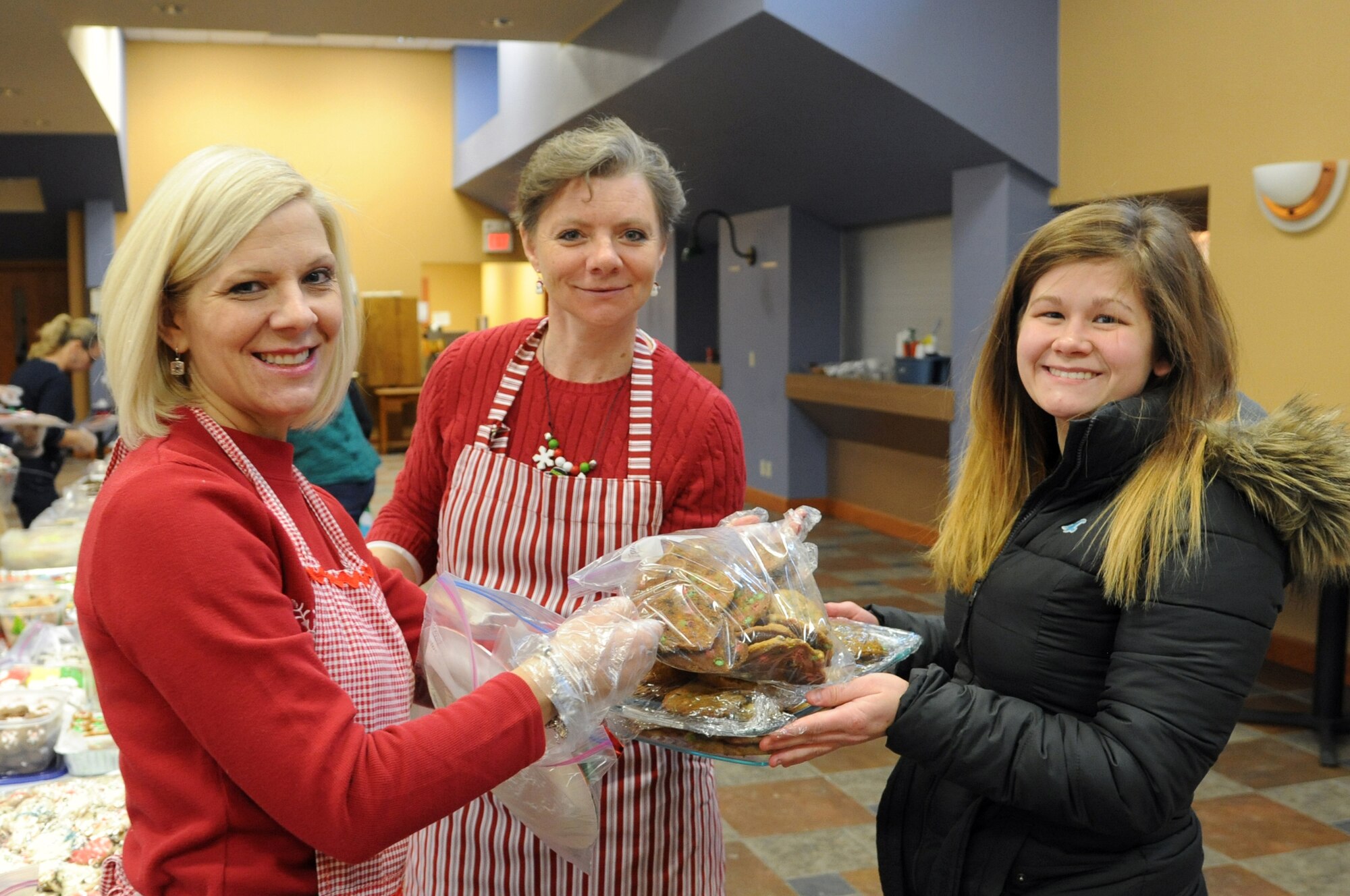(From left) Bonnie Bauman and Becky Duncan, spouses of 319th ABW Commander Col. Paul Bauman and Command Chief Master Sgt. David Duncan, accept a bag of cookies from Amanda Barnett during the annual Holiday Cookie Drive on Grand Forks Air Force Base, N.D., Dec. 8, 2014. Barnett's cookies were part of the more than 500 dozen that were donated for Airmen living in dormitories on base. (U.S. Air Force photo/Staff Sgt. David Dobrydney)