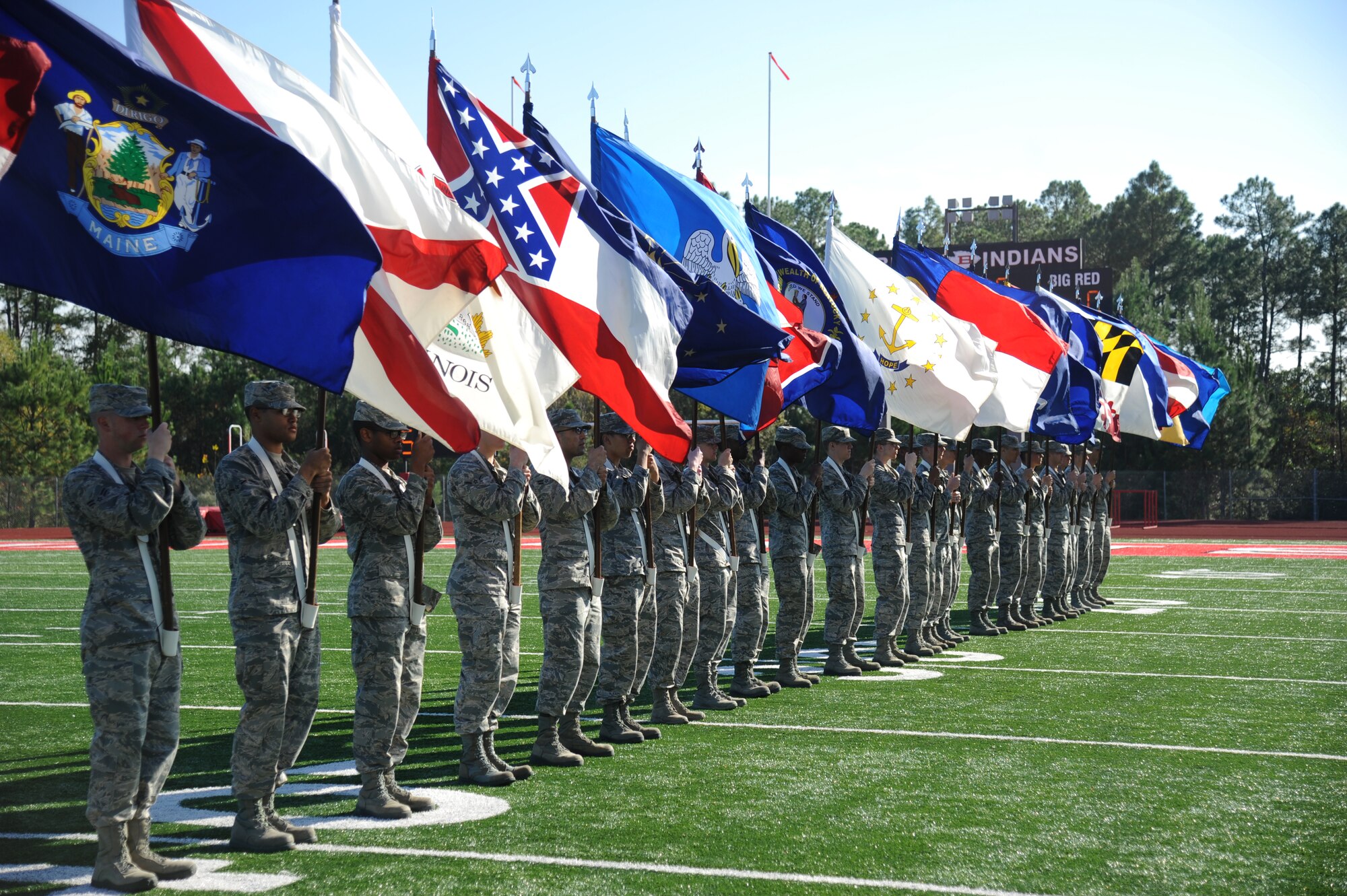 Airmen from Keesler Air Force Base, Miss., line the field with the 50-State flags during a pre-game celebration at the 2014 Mississippi Bowl Dec. 7, 2014, at the Biloxi High School Football Stadium. Brig. Gen. Patrick Higby, 81st Training Wing commander, and the Keesler Honor Guard also participated in the pre-game celebration. (U.S. Air Force photo by Kemberly Groue)