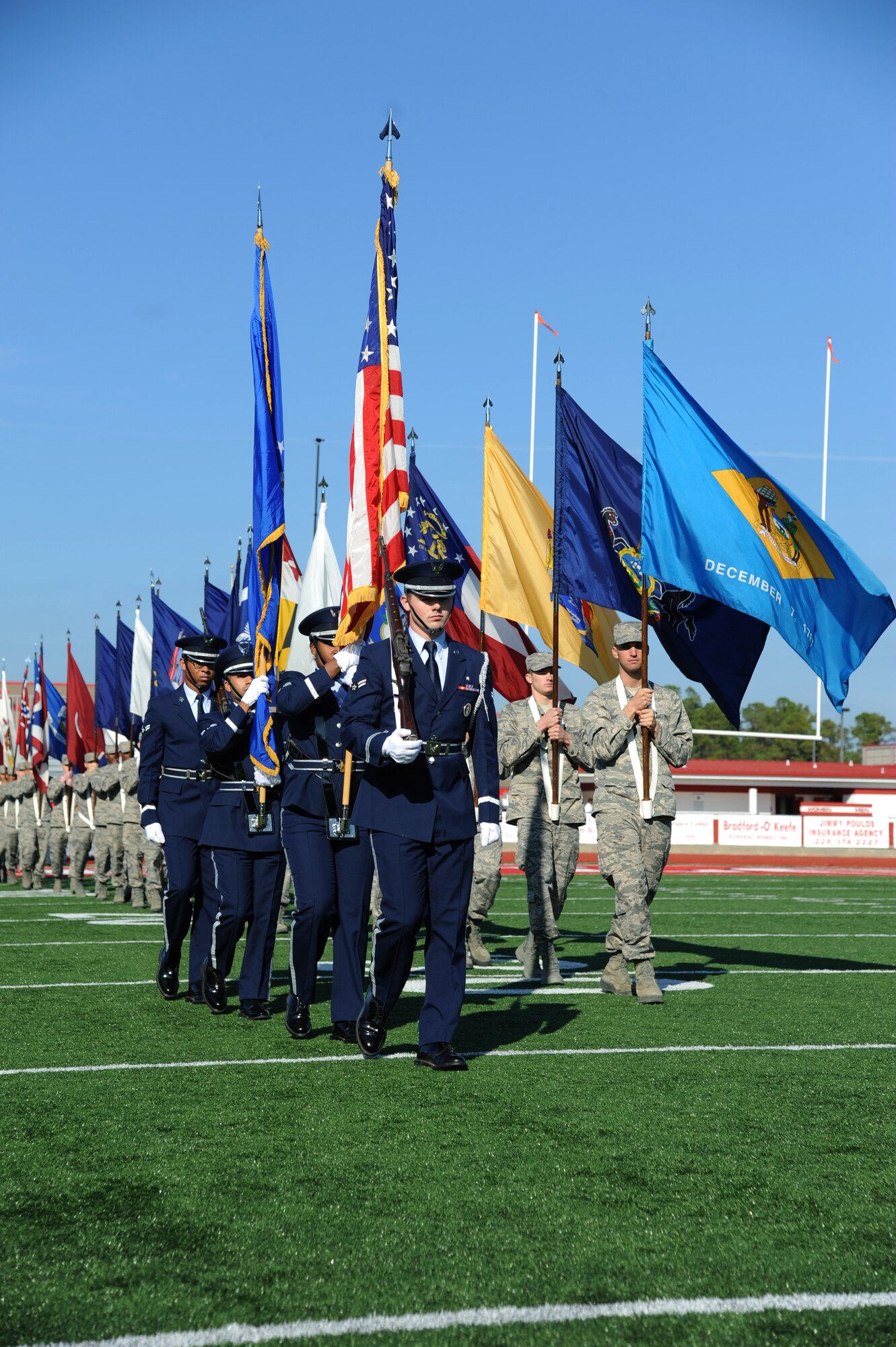 The Keesler Honor Guard and Airmen carrying the 50-State flags enter the field during the 2014 Mississippi Bowl Dec. 7, 2014, at the Biloxi High School Football Stadium. Brig. Gen. Patrick Higby, 81st Training Wing commander, participated in the coin toss during the pre-game celebration. (U.S. Air Force photo by Kemberly Groue)