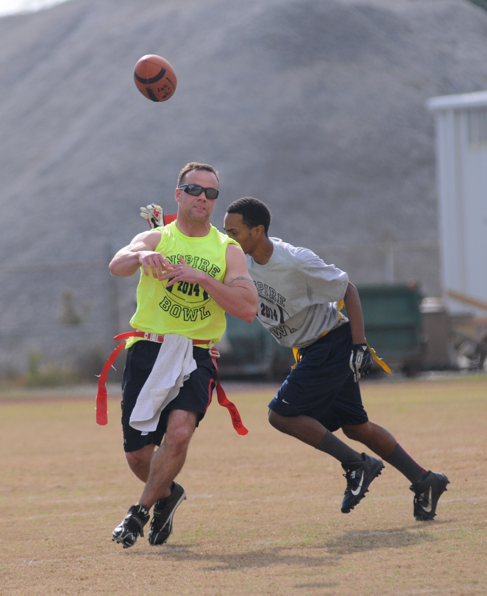Tech. Sgt. Brian Cloutier, 334th Training Squadron air traffic control instructor and Joint Branch team member, makes a pass as Phillip Barnes of D’Iberville and the Mississippi Gulf Coast team pulls his flag during the Nspire Bowl Dec. 6, 2014, at the Salvation Army Kroc Center, Biloxi, Miss.  The Nspire Bowl is a charity event that included two flag-football games with teams made up of military personnel and civilians from local communities.  All donations and profits from the event will be used to purchase gifts for the Salvation Army Angel Tree program. (U.S. Air Force photo by Kemberly Groue)