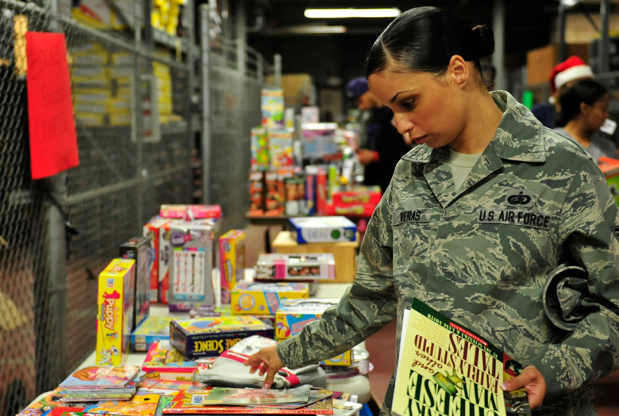 Staff Sgt. Erica Veras decides what book to bring home to her family during the 11th annual toy distribution at Eglin Air Force Base, Fla. Dec. 5. Approximately 2,000 toys were collected by donations made throughout the year. Toys, bikes, books, games, crafts, sports equipment and stuffed animals were given to active-military families in need of assistance during the holidays. (U.S. Air Force photo/Ilka Cole)