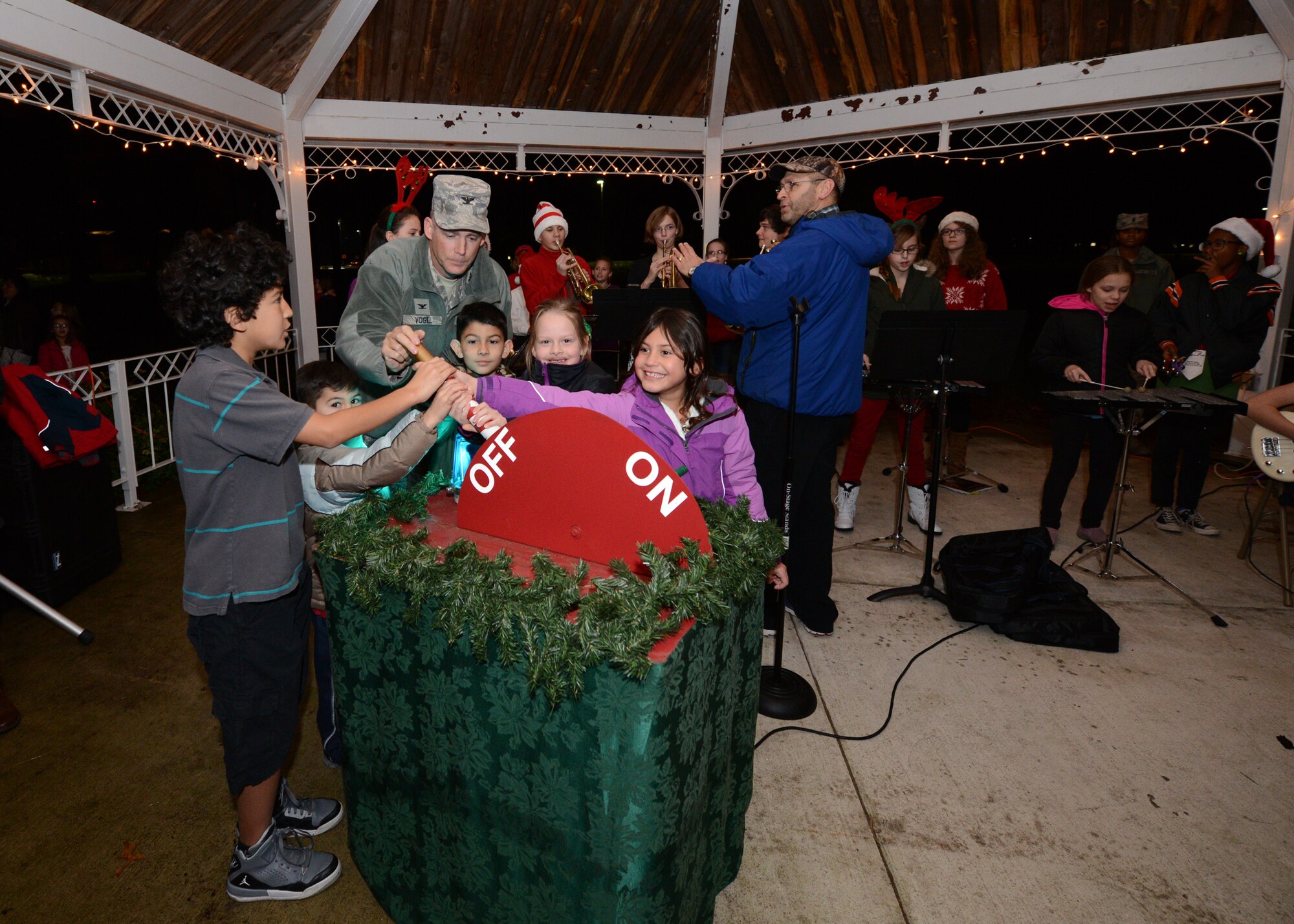 Col. Michael A. Vogel, 66th Air Base Group commander, helps children of deployed military members turn Christmas tree lights on at the Hanscom Air Force Base chapel Dec. 3, 2014.  The Hanscom Middle School band played holiday music as participants waited for Santa.  (U.S. Air Force photo by Walter Santos)