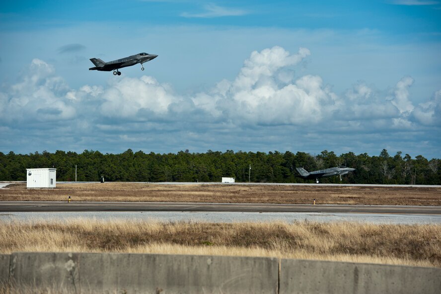 An instructor pilot in an F-35 Lightning II flies overhead to watch Col. Charles Wallace II, 33rd Fighter Wing F-35 Academic Training Center director and F-35 pilot, perform a touch-and-go during his first sortie in the aircraft on Eglin Air Force Base, Fla., Dec. 5, 2014. The ATC mission is to train Air Force, Marine, Navy and international partner operators and maintainers of the F-35. (U.S. Air Force photo/Staff Sgt. Marleah Robertson) 