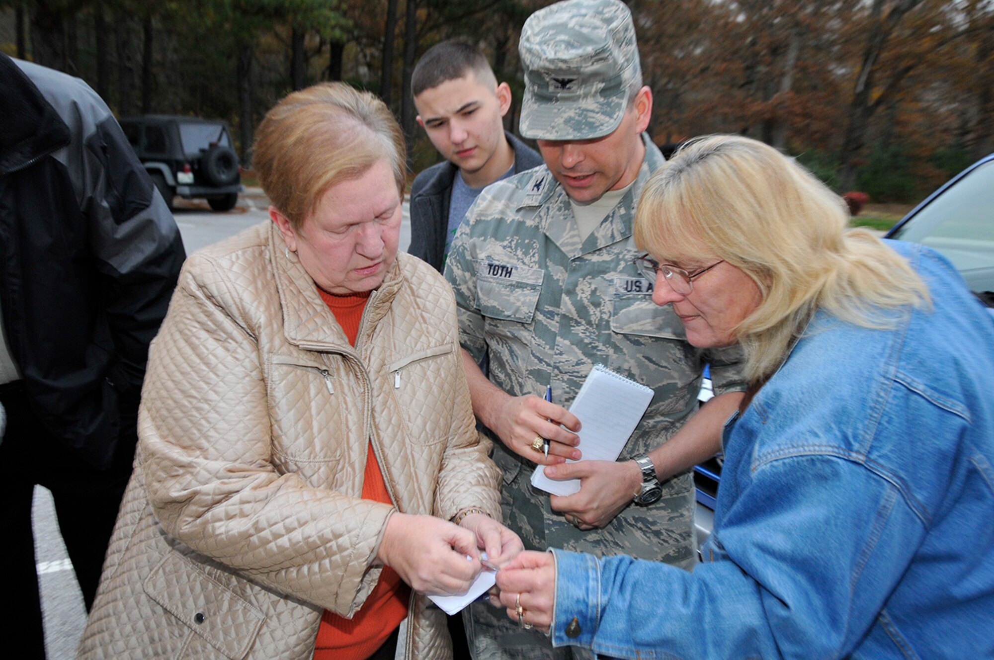 Kenneth Gore’s wife, Ann (left), Col. Raymond Toth (center) and Judith King (right) get a closer look at the inscription on the dog tag, which belonged to Felix Edwin Gore, a Seaman 2nd Class of the U.S. Navy. Daniel Toth (in back) looks on. (Photo by Rick Goodfriend)