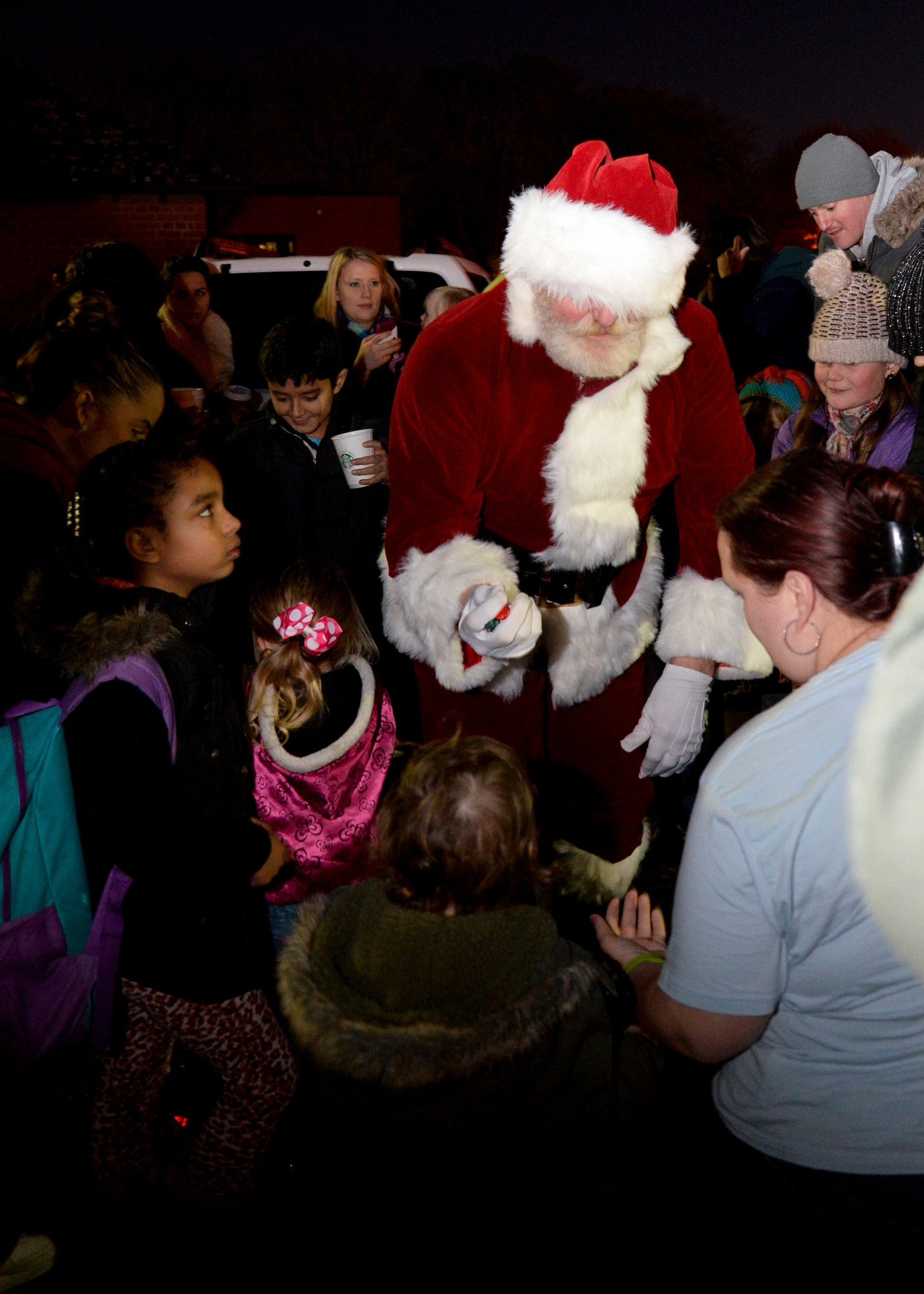 Military families gather around Santa as he passes out candy during the Christmas Tree Lighting ceremony Dec. 5, 2014, on RAF Mildenhall, England. The event kicked off the holiday season for RAF Mildenhall families. (U.S. Air Force photo by Senior Airman Victoria H. Taylor/Released)