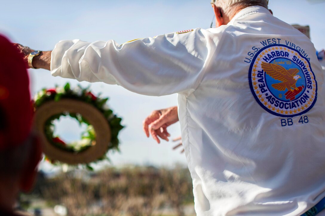 Honorary members of the Pearl Harbor Survivors Association, Chapter 3, toss a wreath during a remembrance ceremony for the 73rd anniversary of the attack on Pearl Harbor at the USS Midway Museum in San Diego, Dec. 7, 2014.