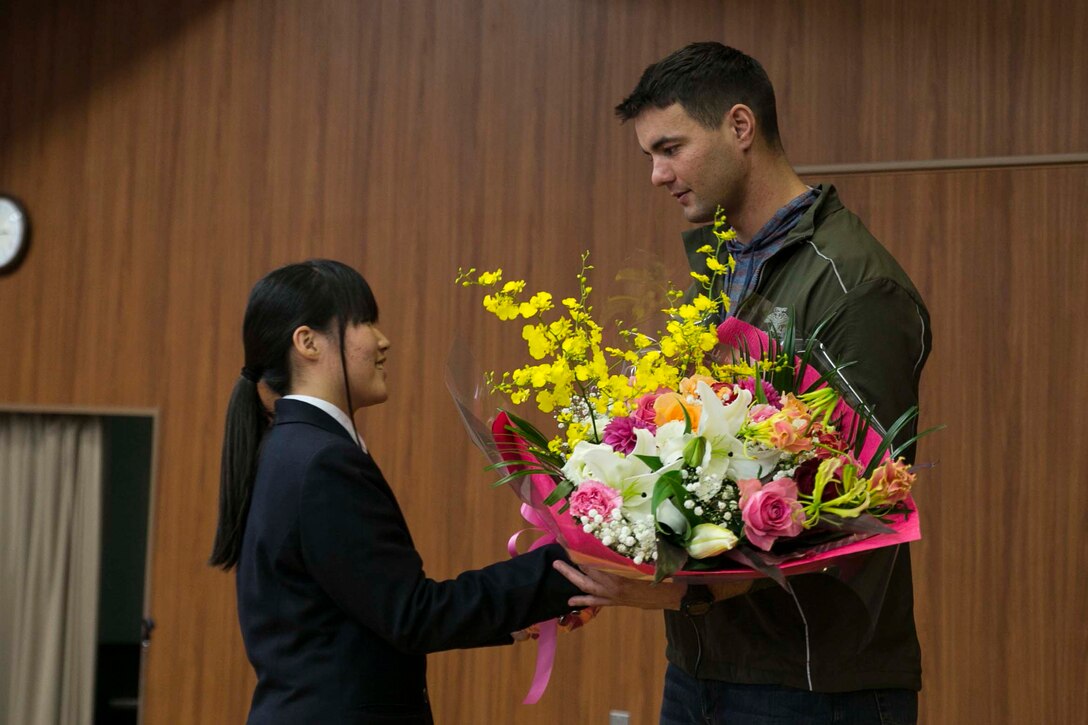 U.S. Marine Staff Sgt. Ryan T. Watson, right, receives a bouquet of flowers from a student Dec. 5 at Chinzei High School in Kumamoto prefecture, Japan. Marines participating in Forest Light 15-1 took a day off from training to visit local high schools to exchange culture lessons with the student. Forest Light is a routine, semi-annual exercise designed to enhance the U.S. and Japan military partnership, solidify regional security agreements, and improve individual and unit-level skills in a bilateral training environment. Watson, from Tulsa, Oklahoma, is an infantry unit leader with 2nd Battalion, 9th Marine Regiment, currently assigned to 4th Marine Regiment, 3rd Marine Division, III Marine Expeditionary Force, under the unit deployment program.