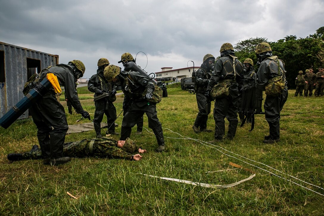Members of the Japan Ground Self-Defense Force’s Special Weapons Protection Unit demonstrate reconnaissance, casualty packaging and extraction drills within a simulated contaminated zone Dec. 1 at Camp Naha. The JGSDF reconnaissance members discovered the mock injured personnel and began to determine the chemical agent, and range of contamination. The team then showed U.S. Marines with a chemical, biological, radiological and nuclear defense background their decontamination process. The JGSDF members are with JGSDF Nuclear Biological Chemical Unit, 15th Brigade. 