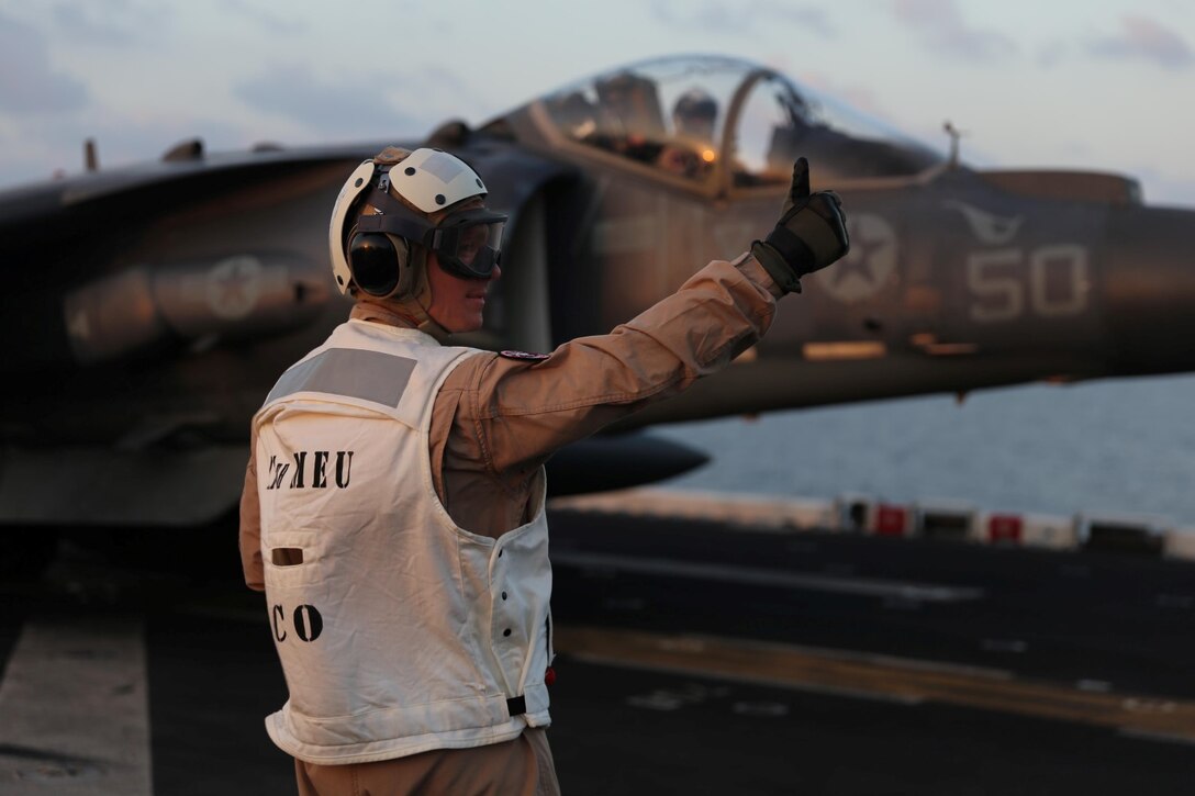 Col. Matthew G. Trollinger, commanding officer, 11th Marine Expeditionary Unit (MEU), signals to an AV-8B Harrier with Marine Medium Tiltrotor Squadron 163 (Reinforced), 11th MEU, aboard amphibious assault ship USS Makin Island (LHD 8), Dec. 4. The Makin Island Amphibious Ready Group (ARG) and the embarked 11th MEU are deployed in support of maritime security operations and theater security cooperation efforts in the U.S. 5th Fleet area of responsibility. (U.S. Marine Corps photos by Cpl. Demetrius Morgan/ Released) 