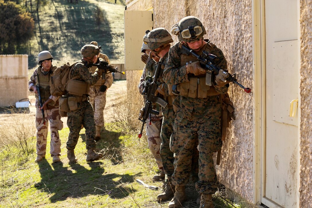 U.S. Marines with Battalion Landing Team 3rd Battalion, 1st Marine Regiment, 15th Marine Expeditionary Unit, and role-players prepare to enter a building while participating in realistic urban training aboard Fort Hunter Liggett, Calif., Dec. 8, 2014.  The Marines were simulating bi-lateral training exercises they could be tasked with while deployed. RUT prepares the 15th MEU's Marines for their upcoming deployment, enhancing their combat skills in environments similar to those they may find in future missions. (U.S. Marine Corps Photo by Sgt. Jamean Berry/Released)