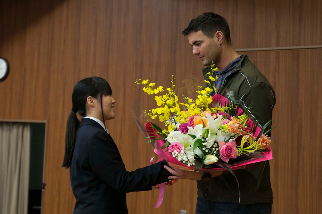 U.S. Marine Staff Sgt. Ryan T. Watson, right, receives a bouquet of flowers from a student Dec. 5 at Chinzei High School in Kumamoto prefecture, Japan. Marines participating in Forest Light 15-1 took a day off from training to visit local high schools to exchange culture lessons with the student. Forest Light is a routine, semi-annual exercise designed to enhance the U.S. and Japan military partnership, solidify regional security agreements, and improve individual and unit-level skills in a bilateral training environment. Watson, from Tulsa, Oklahoma, is an infantry unit leader with 2nd Battalion, 9th Marine Regiment, currently assigned to 4th Marine Regiment, 3rd Marine Division, III Marine Expeditionary Force, under the unit deployment program.