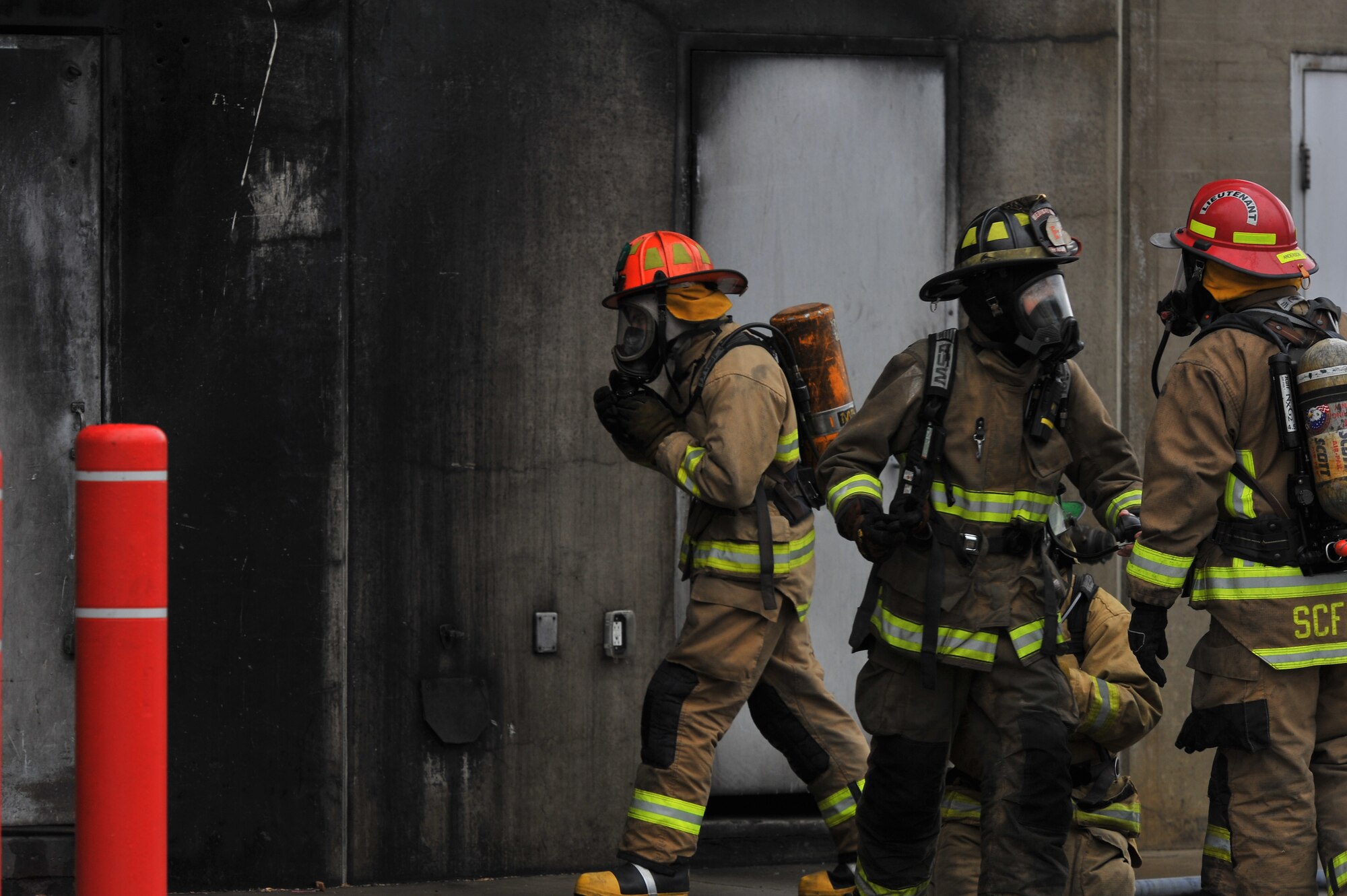 Firefighting recruits from Fairchild Air Force Base, Wash., and the local community enter a smoking building during a multi-company training drill Dec. 6, 2014, in Spokane Valley, Wash.  The 23 recruits participating were part of a four month curriculum conducted by the West Plains Fire Academy.  District 10, Airway heights and Medical Lake stations were part of the all-day training. (U.S. Air Force photo/Staff Sgt. Veronica Montes)