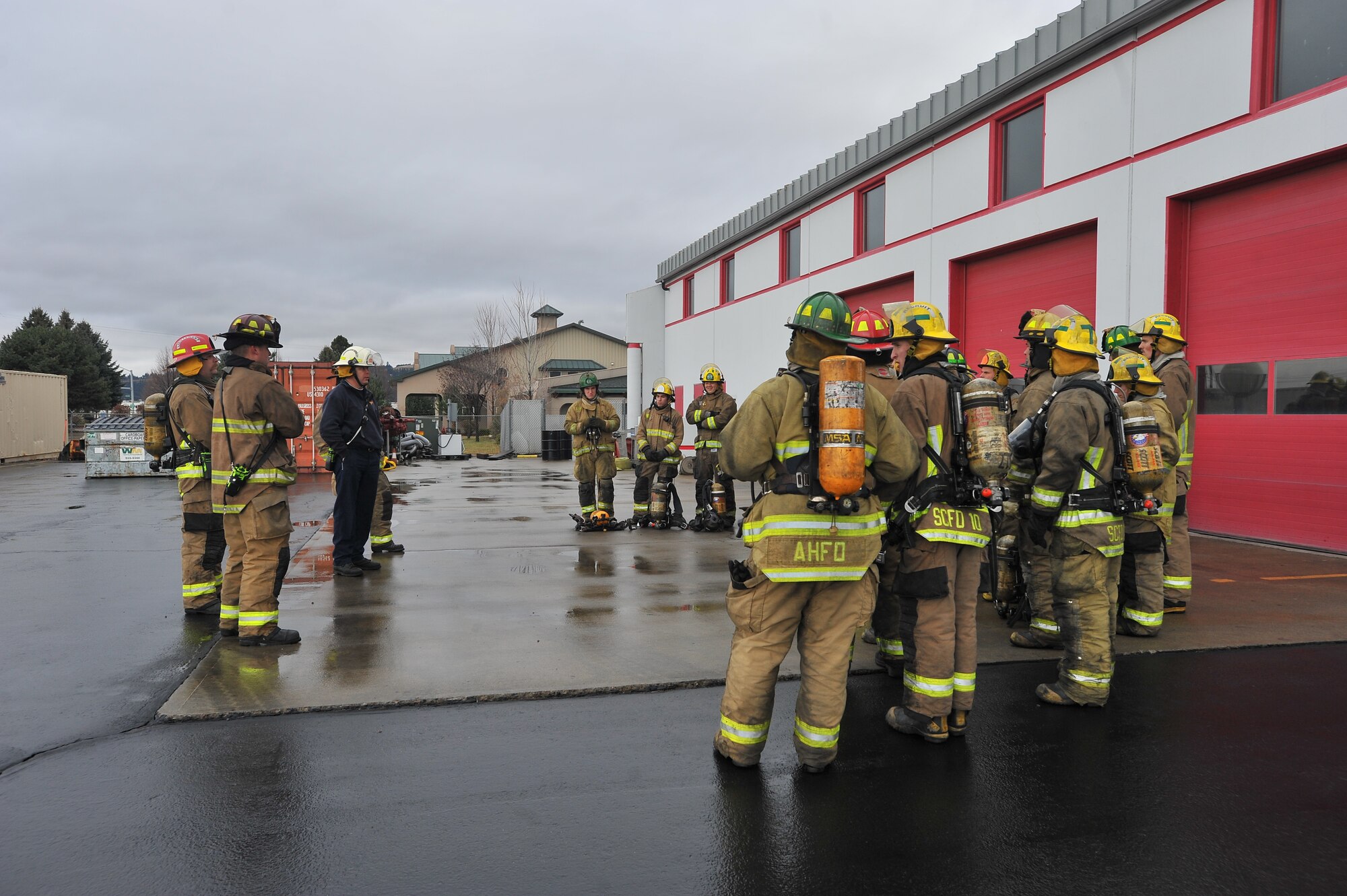 Robert Ladd, District 10 fire department deputy chief, briefs recruits from Fairchild Air Force Base, Wash., and the local community enter a smoking building during a multi-company training drill Dec. 6, 2014, in Spokane Valley, Wash.  The 23 recruits were part of the West Plains Fire Academy and conducted training drills entering a four-story burning building. (U.S. Air Force photo/Staff Sgt. Veronica Montes)