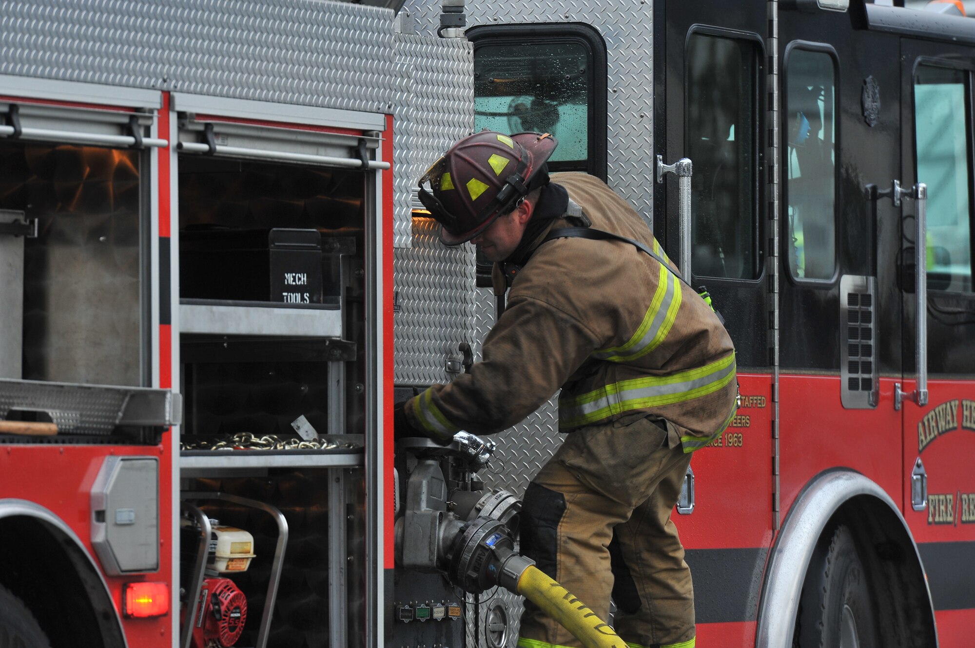 Staff Sgt. Brett Myers, 92nd Security Forces Squadron dog handler, turns on the water hose during a multi-company training drill Dec. 6, 2014, in Spokane Valley, Wash.  Myers is a volunteer fire fighter and was training 23 recruits from the West Plains Fire Academy during the drill. (U.S. Air Force photo/Staff Sgt. Veronica Montes)