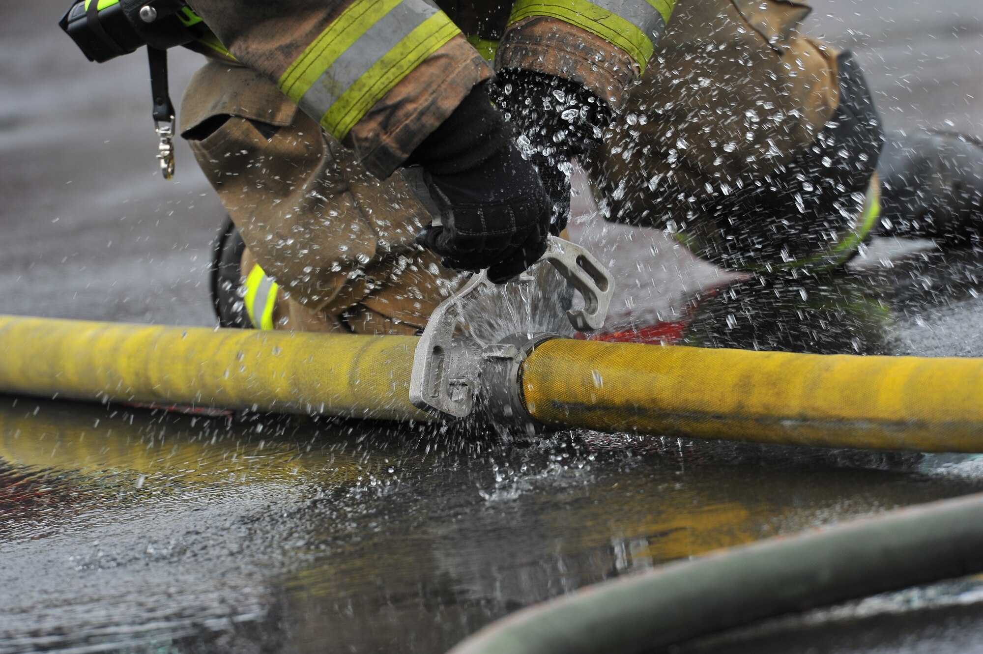 A hose leak is tightened during a multi-company training drill Dec. 6, 2014, in Spokane Valley, Wash.  The training was conducted as part of a four month curriculum conducted by the West Plains Fire Academy.  Both Fairchild Airmen and local community members are currently in the course and will graduate at the end of December with a Fire Fighter One national certification. (U.S. Air Force photo/Staff Sgt. Veronica Montes)