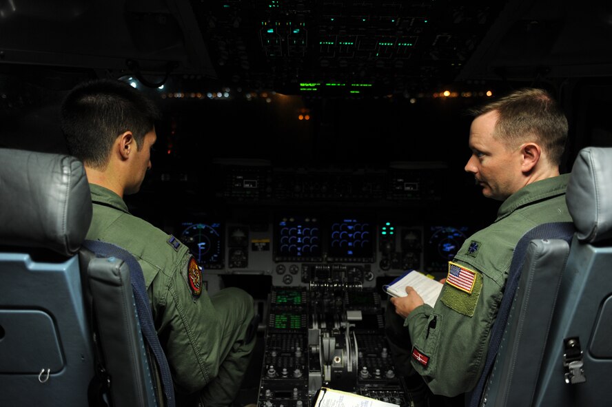 Capt. Chris Bukowski, C-17 Globemaster III pilot from the 535th Airlift Squadron (left) talks with Lt. Col. Davis Milne, 15th Operations Support Squadron commander and aircraft flight commander, while preparing for takeoff at Joint Base Pearl Harbor-Hickam, Hawaii, Dec. 5, 2014. The C-17 aircrew and the Pacific Air Forces' joint component coordination element demonstrated PACAF’s capability to rapidly deploy in less than 24 hours, and will continue their training alongside the 36th Wing Contingency Response Group at Andersen Air Force Base, Guam.