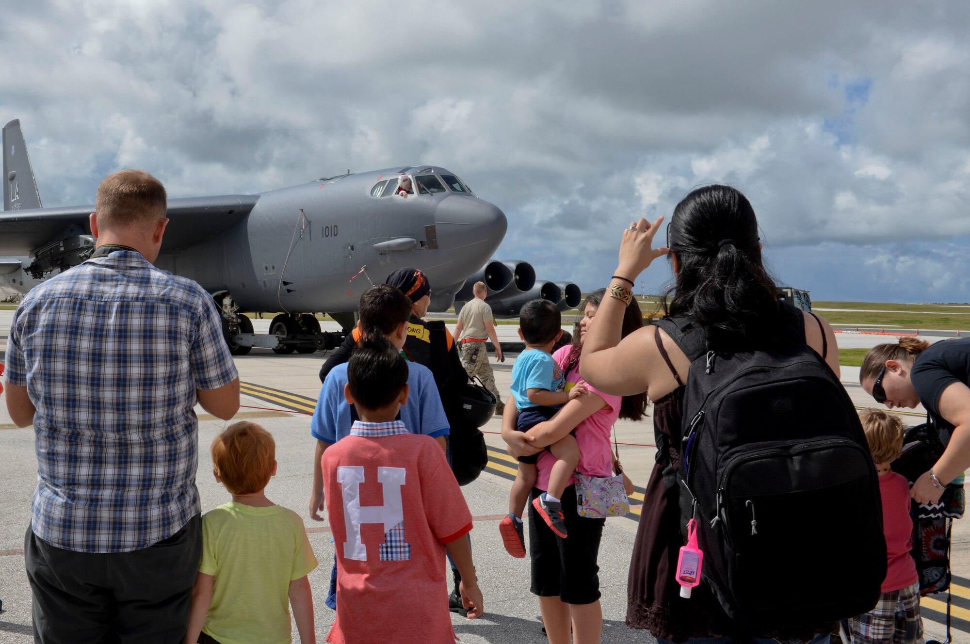 Team Andersen family members cheer and take photos as Santa Claus approaches in a B-52 Stratofortress, Dec. 7, 2014, at Andersen Air Force Base, Guam.  Andersen held a holiday party that included games, a bounce house and a chance to take photos with Santa Claus.  (U.S. Air Force photo by Staff Sgt. Robert Hicks/Released)