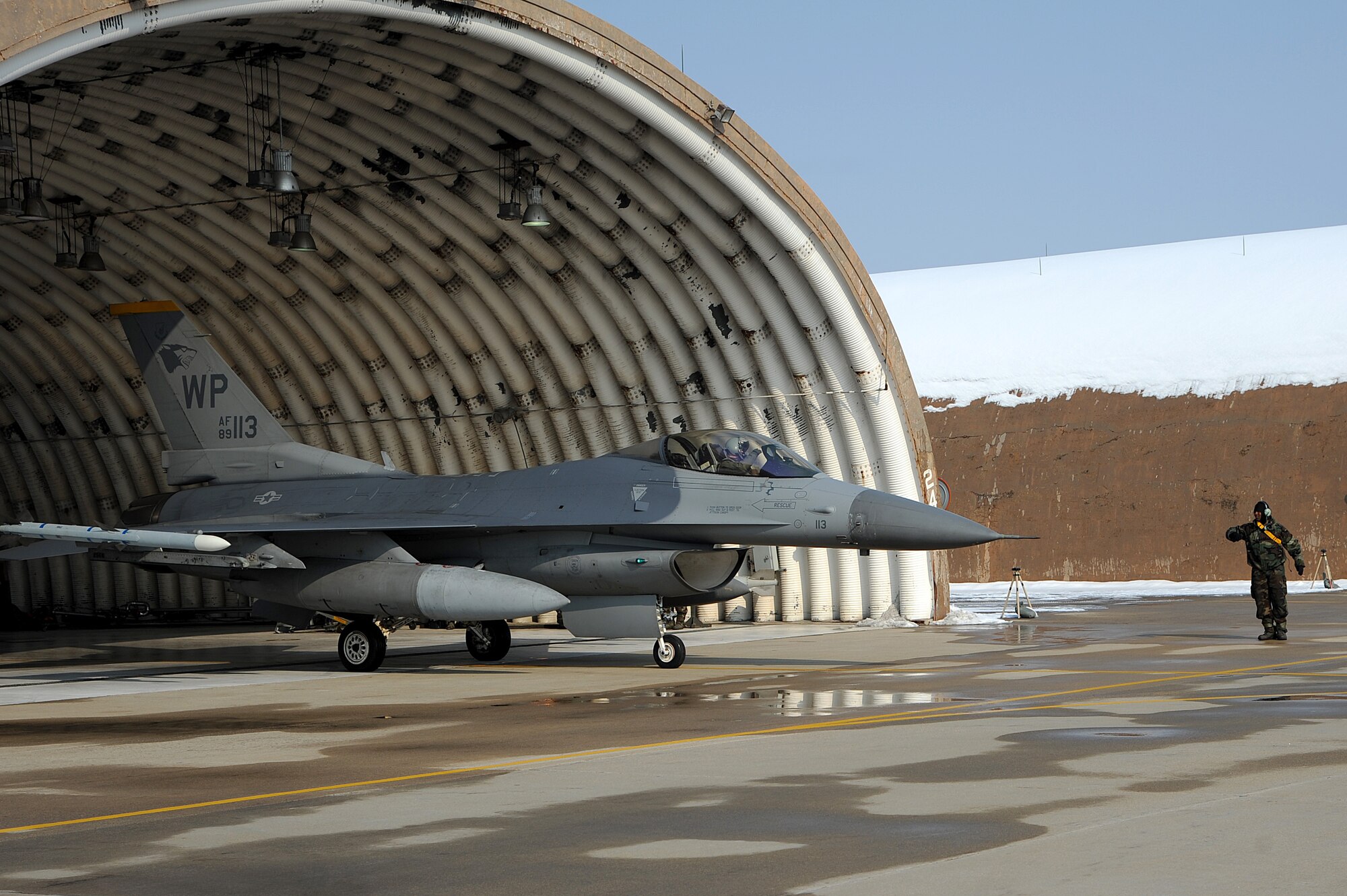A Wolf Pack crew chief taxi's out an F-16 Fighting Falcon during Exercise Beverly Bulldog 15-1 at Kunsan Air Base, Republic of Korea, Dec. 8, 2014. The eight-day exercise took place in an austere environment that tested the Wolf Pack’s ability to respond to wartime and armistice threats, and showcased their ability to persevere through extreme temperatures and more than eight inches of snow. (U.S. Air Force photo by Senior Airman Divine Cox/Released) 
