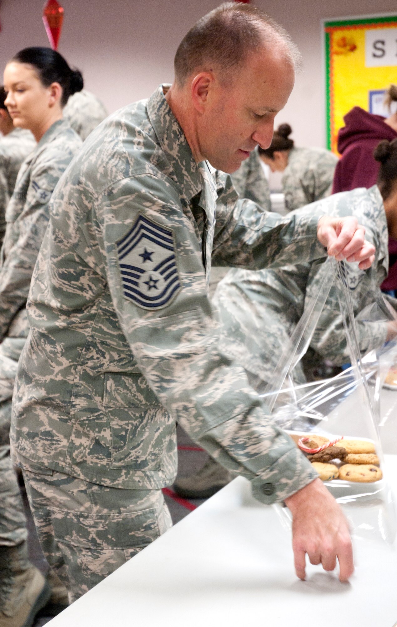 Chief Master Sgt. Samuel Couch, 90th Missile Wing command chief, wraps a tray of cookies during the cookie drive Dec. 8, 2014, in the Chapel Activities Center on F.E. Warren Air Force Base, Wyo. The cookie drive is an annual event that occurs across the Air Force as a way to show appreciation for Airmen during the holidays. (U.S. Air Force photo/Airman 1st Class Malcolm Mayfield)