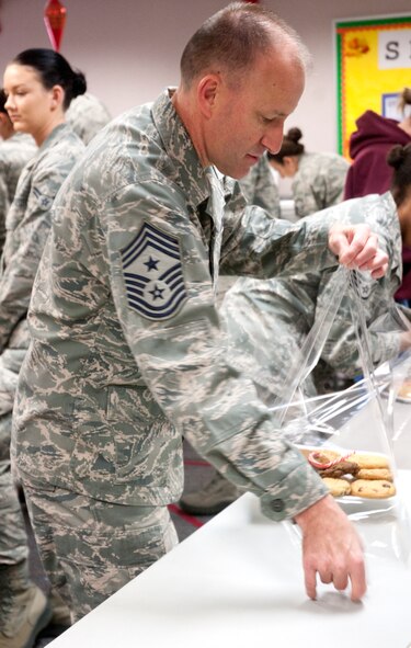 Chief Master Sgt. Samuel Couch, 90th Missile Wing command chief, wraps a tray of cookies during the cookie drive Dec. 8, 2014, in the Chapel Activities Center on F.E. Warren Air Force Base, Wyo. The cookie drive is an annual event that occurs across the Air Force as a way to show appreciation for Airmen during the holidays. (U.S. Air Force photo/Airman 1st Class Malcolm Mayfield)