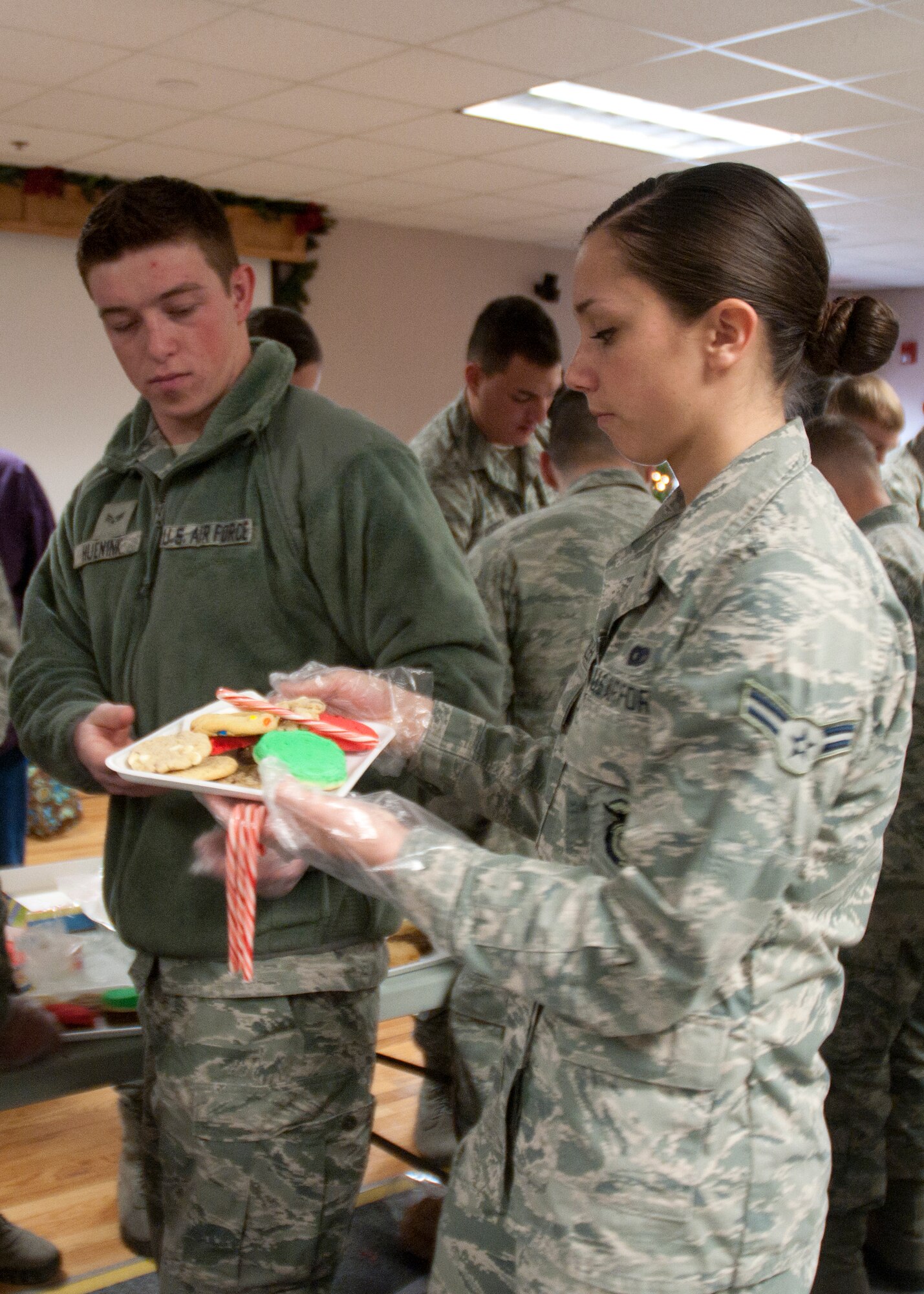 Senior Airmen Thomas Huenink, 790th Missile Security Forces Squadron convoy response force, passes a tray of cookies to Airman 1st Class Kristin Pressler, 790th MSFS CRF, during the wing’s annual cookie drive Dec. 8, 2014, in the Chapel Activities Center on F.E. Warren Air Force Base, Wyo. Airmen from the 790th MSFS, Airman Leadership School and other various organizations helped package cookies for Base distribution. (U.S. Air Force photo/Airman 1st Class Malcolm Mayfield)