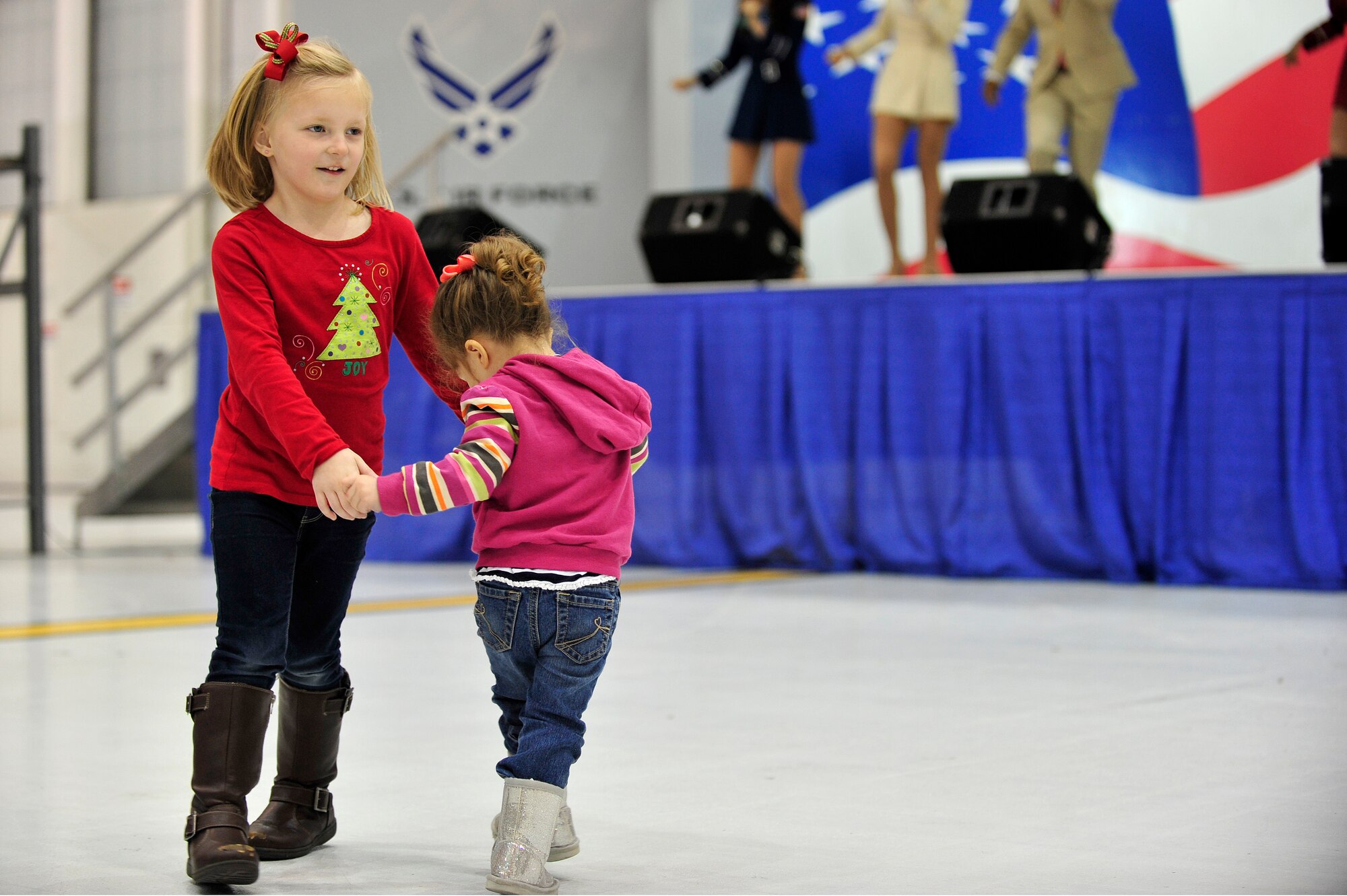 Two young members of Team Seymour dance while the United Service Organization Show Troupe sings during a performance at Seymour Johnson Air Force Base, North Carolina, Dec. 6, 2014. The Show Troupe, made up of four singers and a support team, provided an hour-long set for members of Team Seymour. They annually perform musical entertainment for more than 600,000 service members and families across the globe. (U.S. Air Force photo/Amn Shawna L. Keyes)