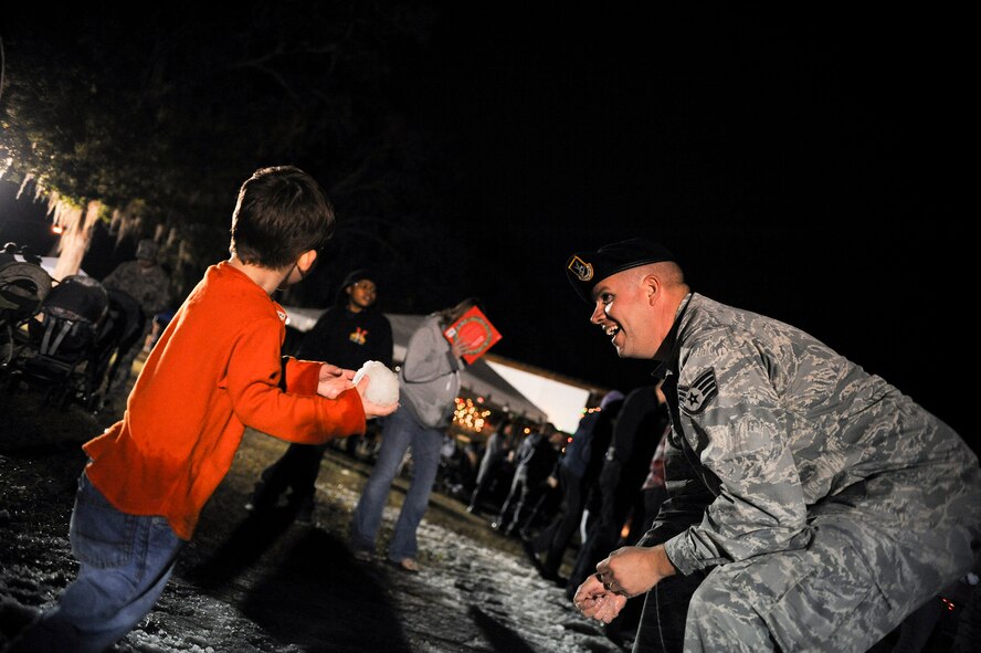 U.S. Air Force Staff Sgt. Timothy Jeffrey, 23d Security Forces Squadron, plays in the snow with Nathaniel Brown, son of Tech Sgt. Johnathon Brown, 23d Civil Engineer Squadron, during the Annual Base Tree Lighting and Holiday Parade Dec. 5, 2014 at Moody Air Force Base, Ga. The annual event provides Team Moody an opportunity to enjoy an evening filled with holiday cheer and recognizes deployed Airmen and their families. (U.S. Air Force photo by Andrea Jenkins/Released)