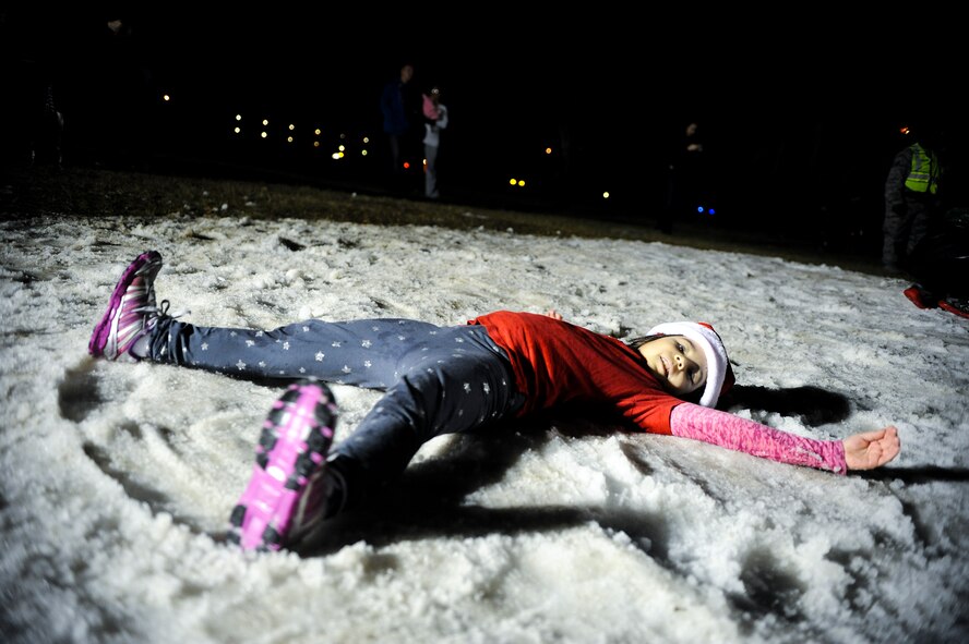 Chloe, daughter of U.S. Air Force Senior Master Sgt. Jeannette Zhong, 23d Comptroller Squadron, makes a snow angel during the Annual Base Tree Lighting and Holiday Parade, Dec. 5, 2014 at Moody Air Force Base, Ga. Snow was provided by snow makers to give the children a winter feel in south Georgia. (U.S. Air Force photo by Andrea Jenkins/Released)
