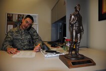 A trophy in the shape of an Air Force Security Forces Airman appears to stand guard by the desk’s edge as Senior Master Sgt. Jerald D. Thomas, 319th Security Forces Squadron operations superintendent, reviews documents at his office Dec. 9, 2014, at the Base Defense Operations Center on Grand Forks Air Force Base, N.D. The trophy is one of several awards that decorate Thomas’s office, who recently won his third major command –level award. (U.S. Air Force photo/Staff Sgt. Luis Loza Gutierrez)