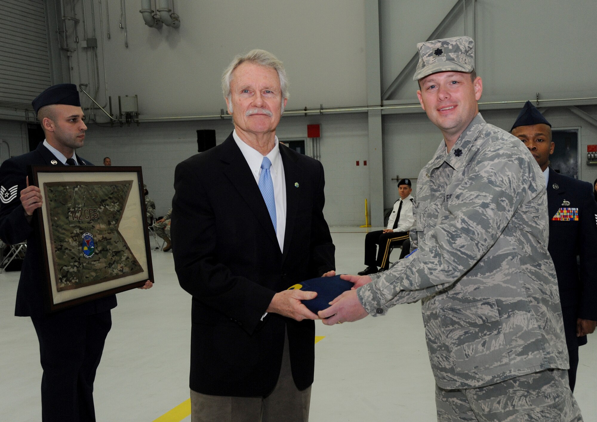 Oregon Governor John Kitzhaber receives the Oregon flag that was flown during deployment from Lt. Col. Jason Lay, 142nd Fighter Wing Civil Engineer Squadron Commander, during the formal Demobilization Ceremony at the Portland Air National Guard Base, Ore., Dec. 7, 2014. The Airmen recently returned from overseas deployment assignments to support Operation Enduring Freedom. (U.S. Air National Guard photo by Tech. Sgt. John Hughel, 142nd Fighter Wing Public Affairs/Released)