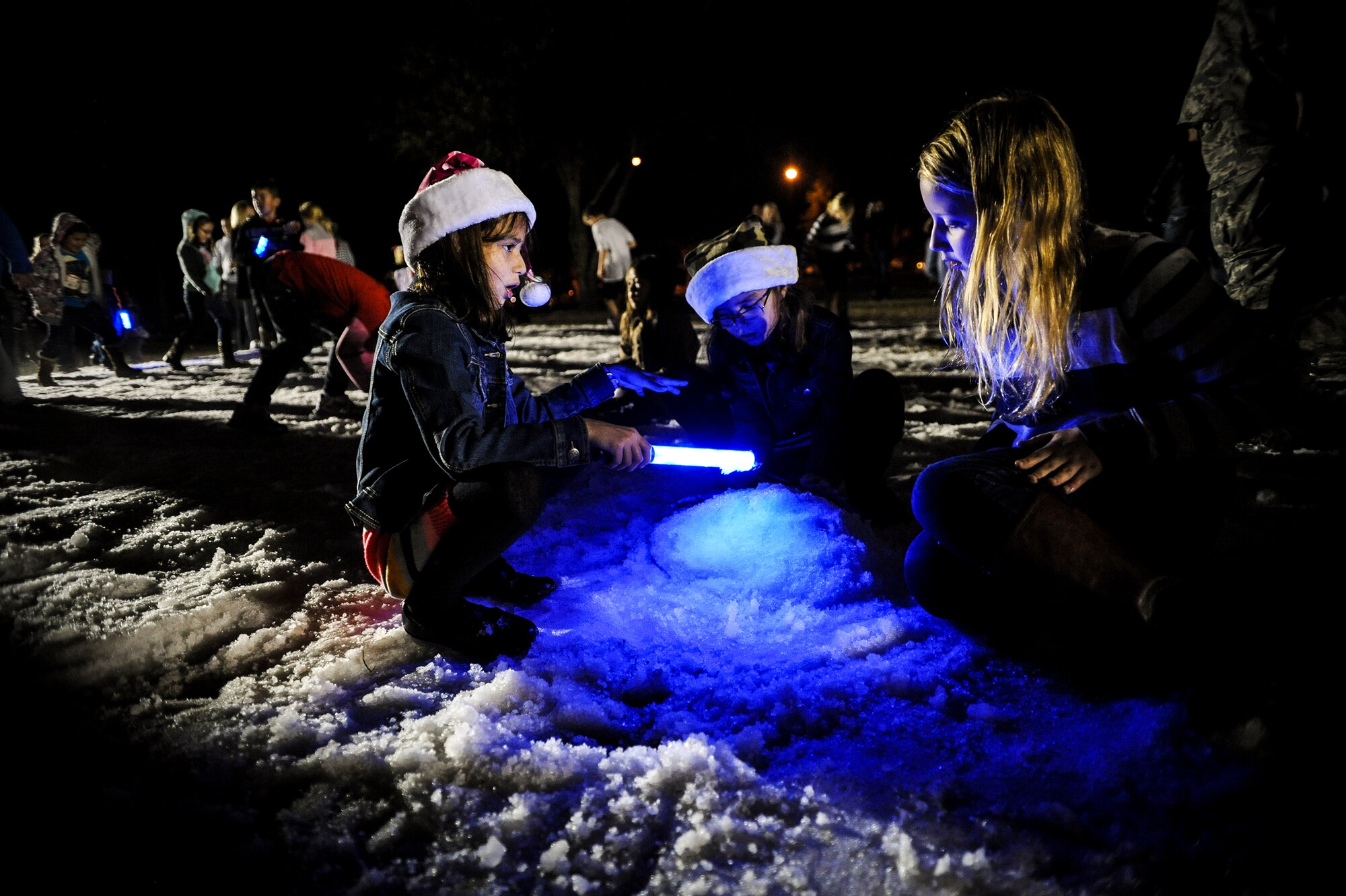 Children play in the snow during the Annual Base Tree Lighting and Holiday Parade, Dec. 5, 2014 at Moody Air Force Base, Ga. Over 80,000 pounds of ice blocks were placed inside a snow gun to make a two foot deep snow pit and create a winter atmosphere for the holiday event. (U.S. Air Force photo by Andrea Jenkins/Released)