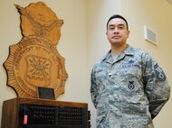 Senior Master Sgt. Jerald D. Thomas, 319th Security Forces Squadron operations superintendent, poses for a photo by a historical display featuring a large wooden Air Force Security Forces police badge and vintage switchboard, Dec. 9, 2014, at the Base Defense Operations Center on Grand Forks Air Force Base, N.D. Thomas was named the Air Mobility Command's Outstanding Security Forces Support Staff Senior NCO for 2014. (U.S. Air Force photo/Staff Sgt. Luis Loza Gutierrez)
