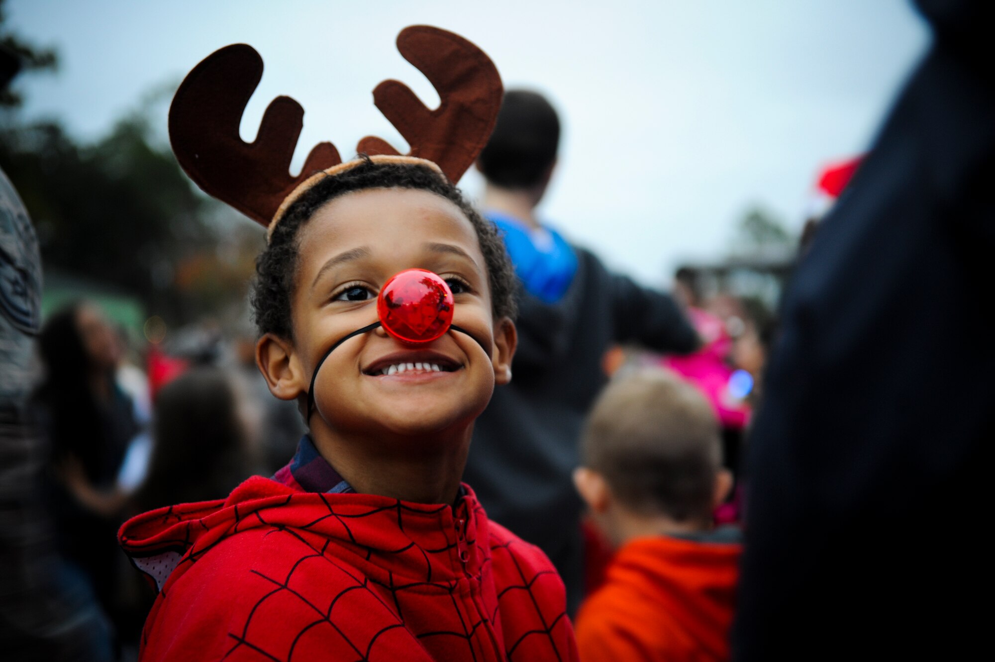 Isaiah, 6, son of U.S. Air Force Staff Sgt. Divonte Brown, 23d Civil Engineer Squadron, stops caroling to smile for the crowd during the Annual Base Tree Lighting and Holiday Parade Dec. 5, 2014 at Moody Air Force Base, Ga. Children from Youth Programs performed several holiday carols for the audience. (U.S. Air Force photo by Andrea Jenkins/Released)