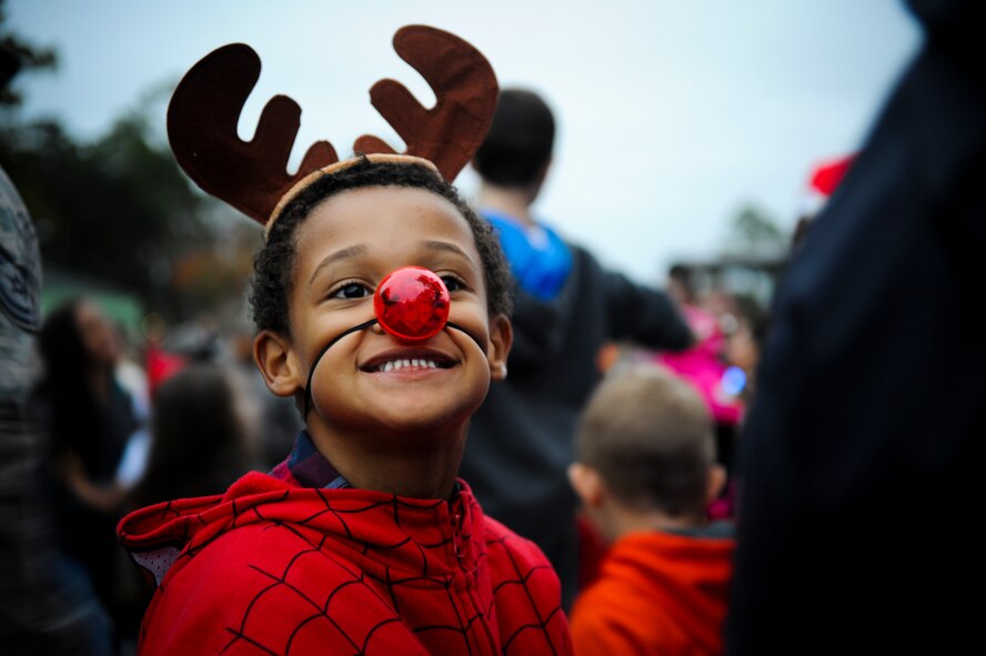 Isaiah, 6, son of U.S. Air Force Staff Sgt. Divonte Brown, 23d Civil Engineer Squadron, stops caroling to smile for the crowd during the Annual Base Tree Lighting and Holiday Parade Dec. 5, 2014 at Moody Air Force Base, Ga. Children from Youth Programs performed several holiday carols for the audience. (U.S. Air Force photo by Andrea Jenkins/Released)