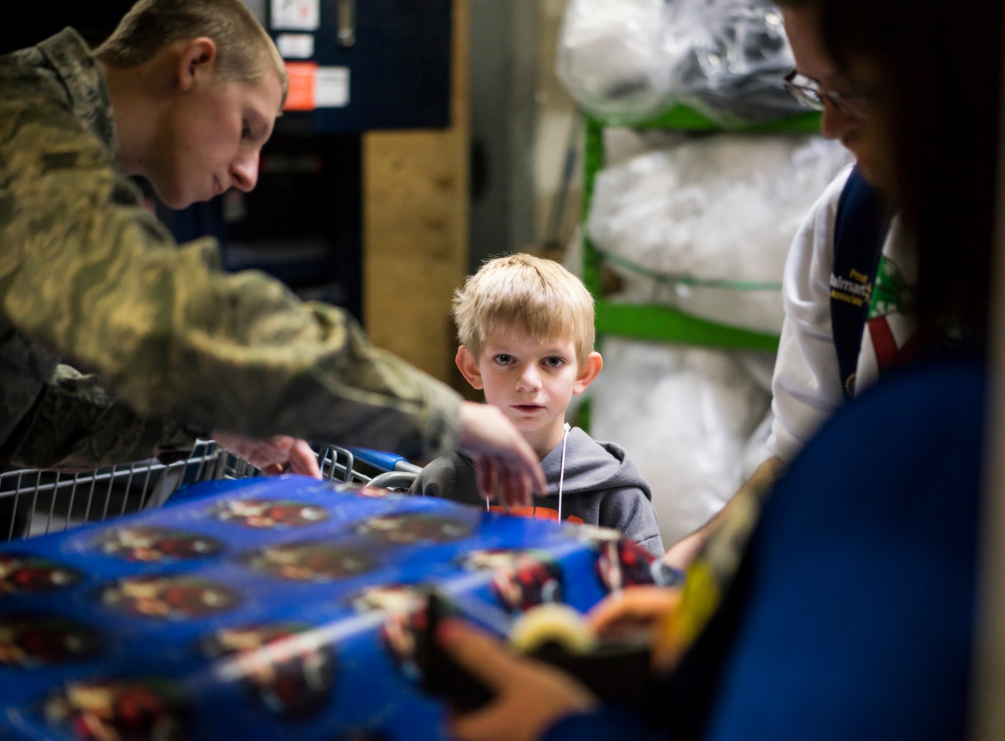 Tyler Reid, center, looks up while volunteers wrap presents he selected during a "Shop with a Cop" event at the Walmart in Mountain Home Idaho.  Many of the children who participated bought gifts for their families instead of themselves. (U.S. Air Force photo/Tech. Sgt. Samuel Morse)