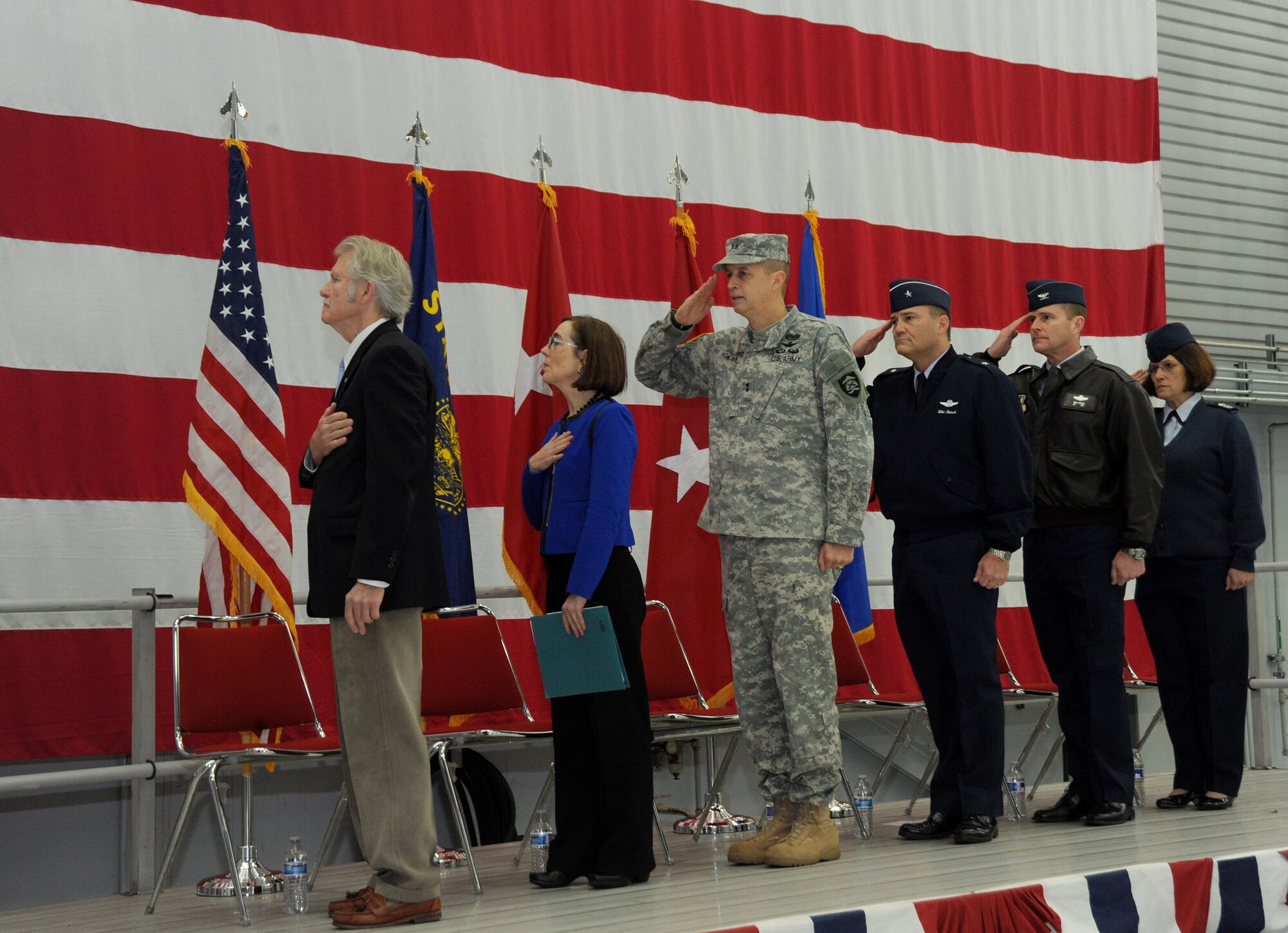 Members of the official party pause and render respect for the American flag during the playing of the National Anthem as part of the formal Demobilization Ceremony at the Portland Air National Guard Base, Ore., Dec. 7, 2014. The Airmen recently returned from overseas deployment assignments to support Operation Enduring Freedom. (U.S. Air National Guard photo by Tech. Sgt. John Hughel, 142nd Fighter Wing Public Affairs/Released)