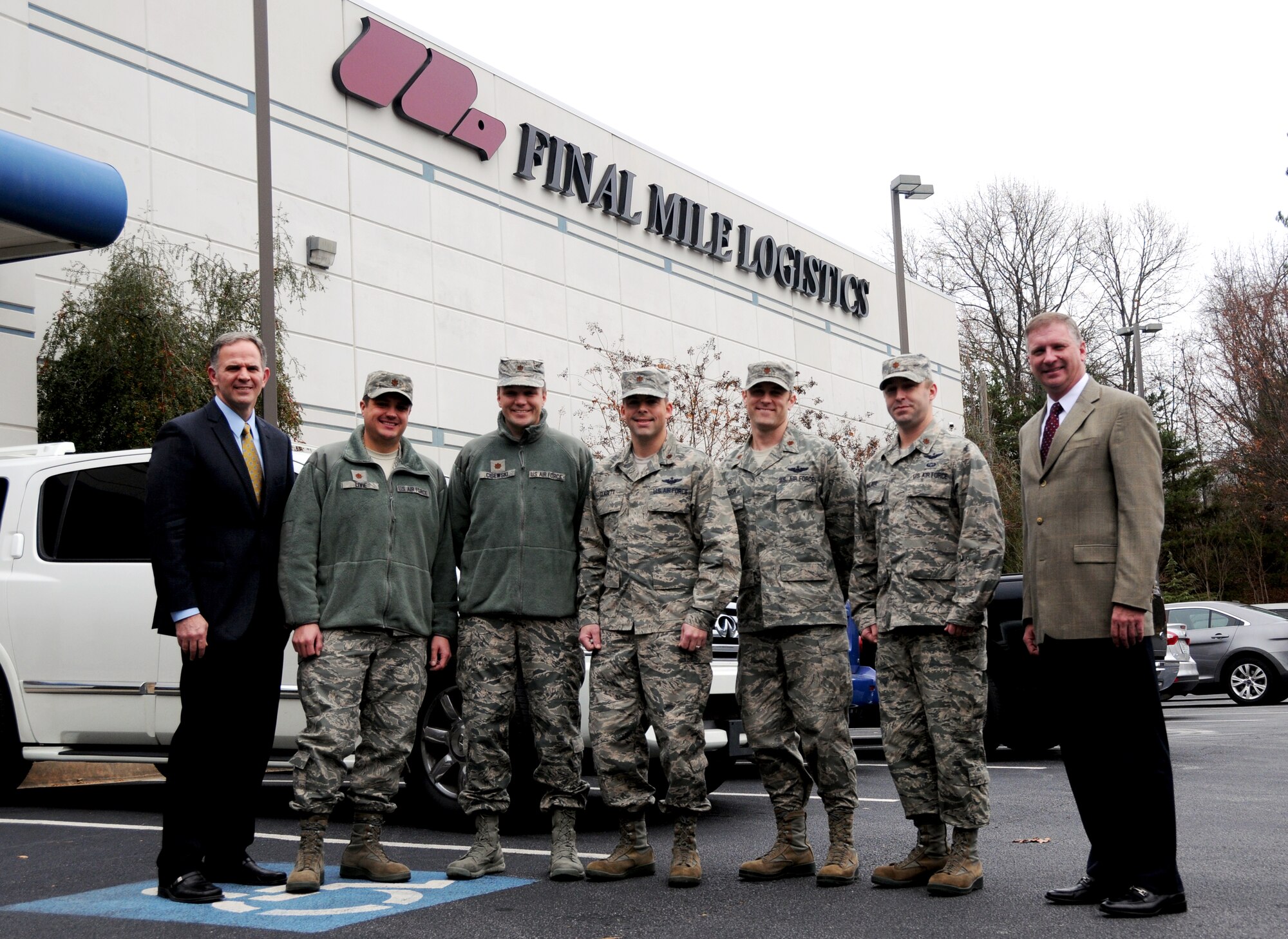 Majors from Air Mobility Command pose for a photo with Colice Powell and Mark Gordon, both Final Mile Logistics, at FML in Atlanta, Ga., Dec. 8, 2014. Five majors from AMC came to the Atlanta area the week of Dec. 8 through 10 to speak to civilian business leaders as part of the Joint Mobility Fellowship Program. (U.S. Air Force photo by Senior Airman Daniel Phelps)