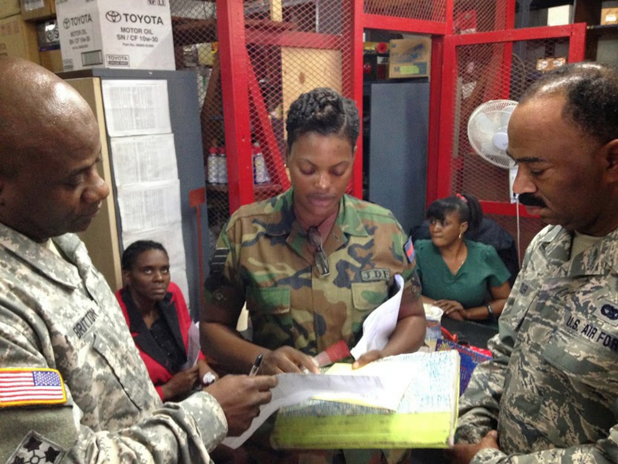 Jamaica Defence Force Sgt. Amelia Jones Ellis, technical store representative of the stores shop, explains her shop’s mission to Chief Warrant Officer 2 Courtney Britton, D.C. National Guard team lead and maintenance manager (left), and Senior Airman Renardo Butler, vehicle mechanic of the 113th Wing, D.C. Air National Guard (right). As part of the State Partnership Program, the D.C. National Guard team of Air Force and Army wheeled vehicle maintenance experts are working alongside their JDF counterparts to exchange information and learn from each other. (U.S. Air National Guard photo by Capt. Renee Lee)